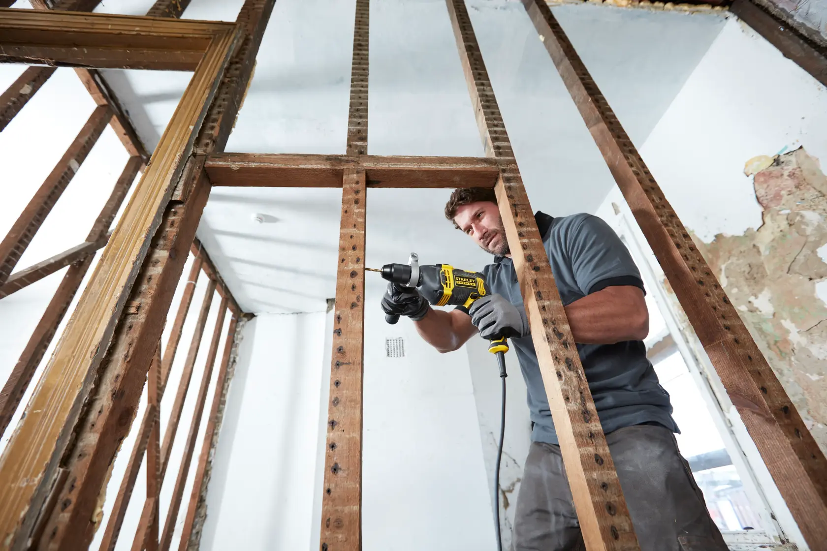 STANLEY FMEH750 corded drill used by a worker in a construction site, horizontal angle.