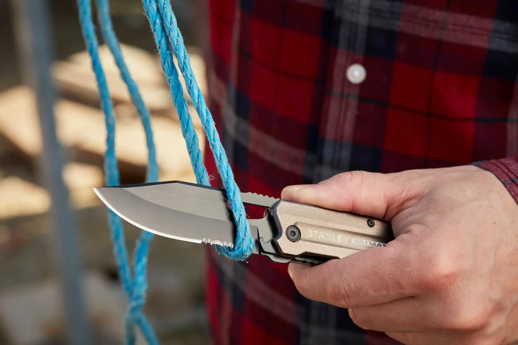 STANLEY FMHT0-10311 folding knife cutting blue rope, close-up outdoor view.