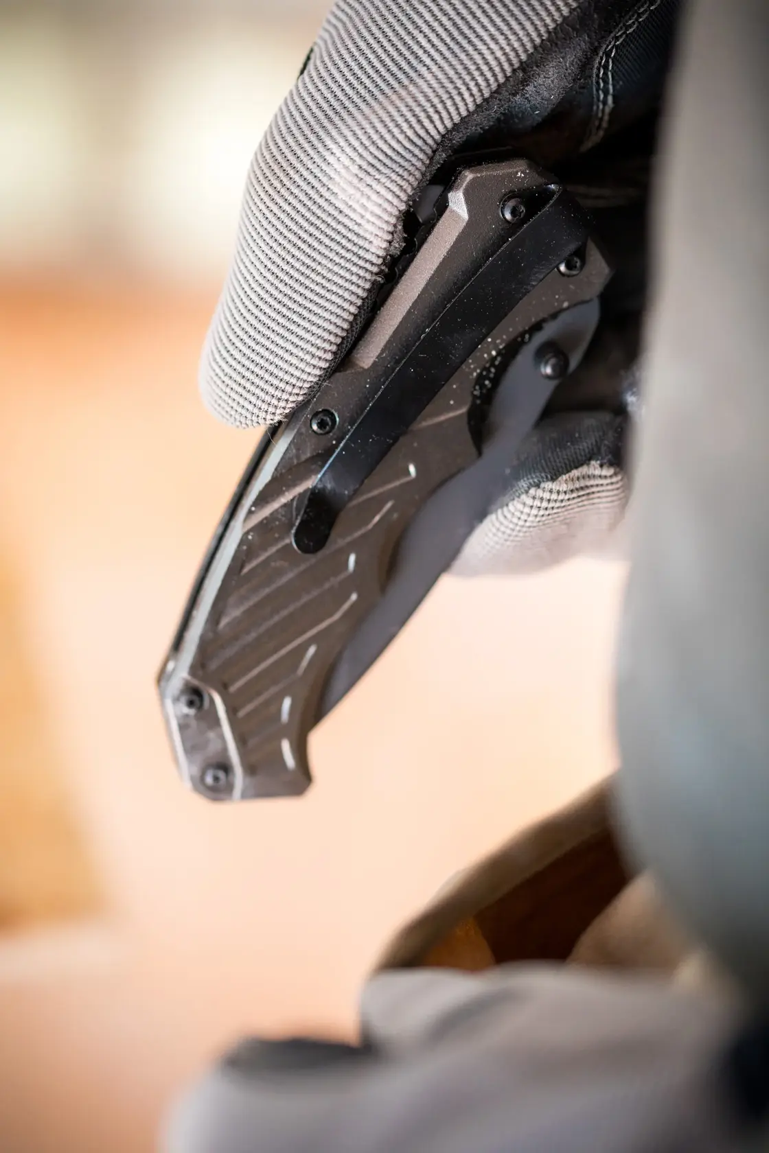 Close-up photo of a gloved hand holding a STANLEY FMHT0-10311 folding utility knife with black handle.