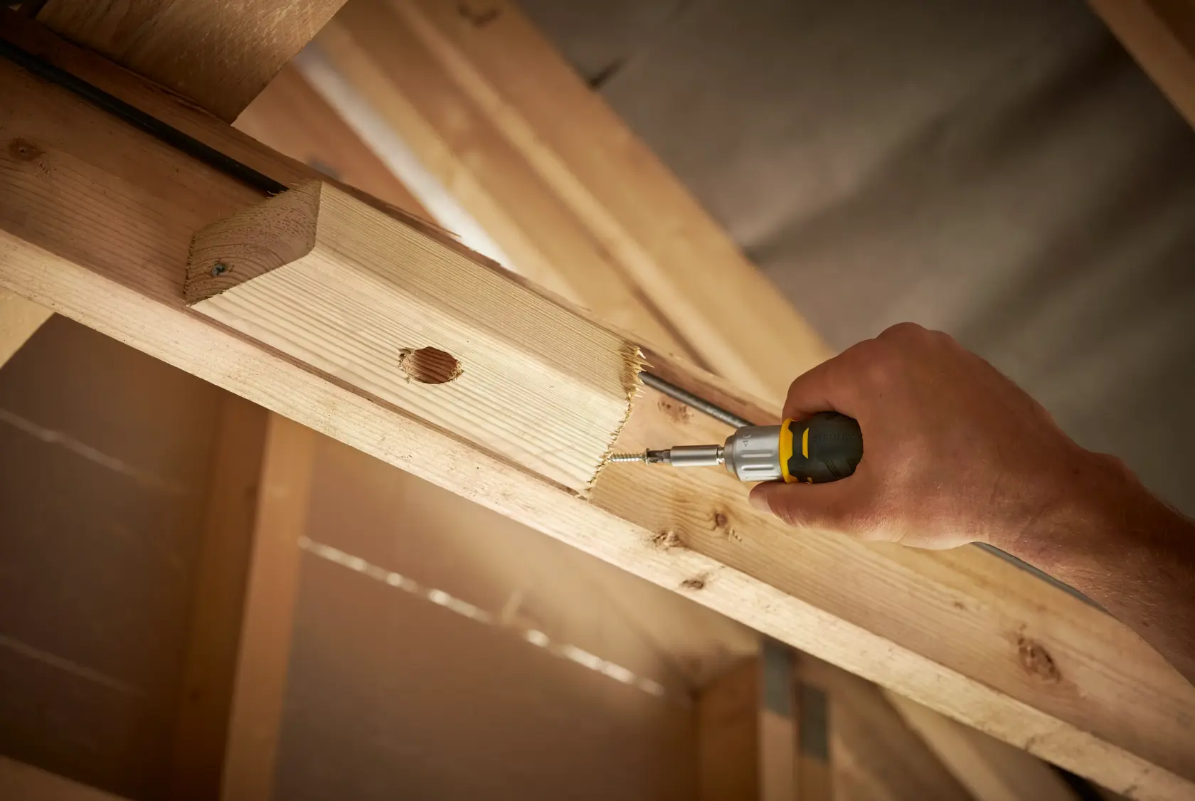 STANLEY FMHT0-62688 screwdriver in use tightening screw on wooden beam, close-up photography.