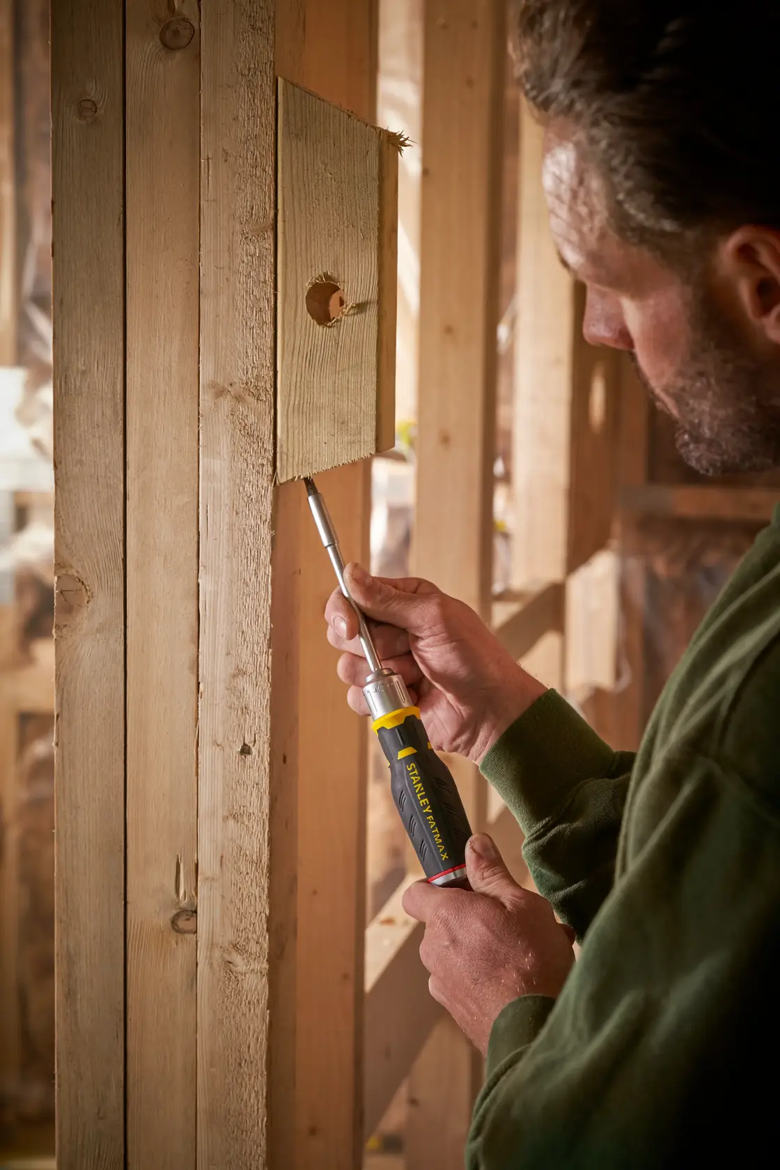 Photo of STANLEY FMHT0-62690 screwdriver in use on wooden framing, product held in hand.