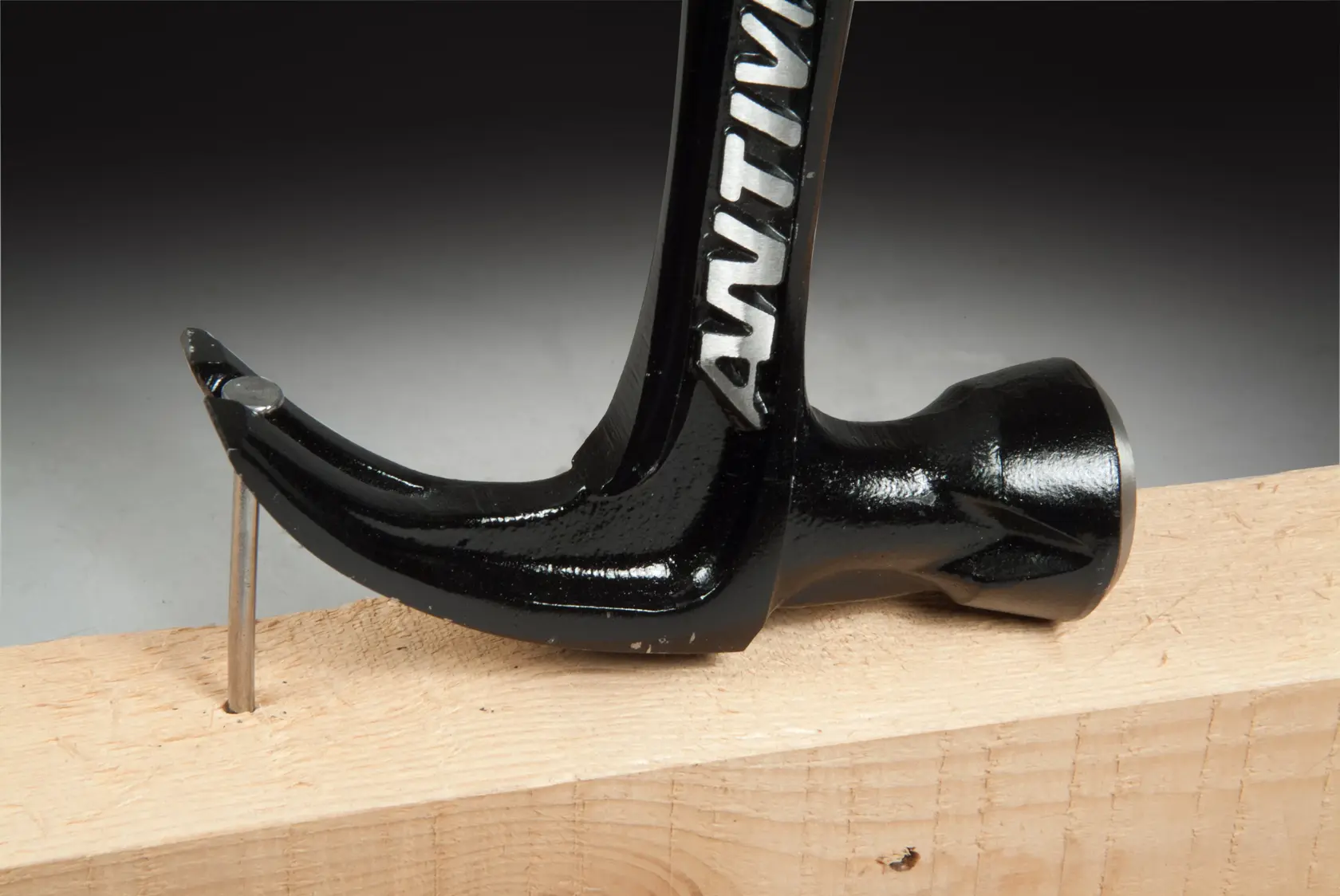 STANLEY FMHT1-51277 claw hammer removing nail from wood, close-up side view.