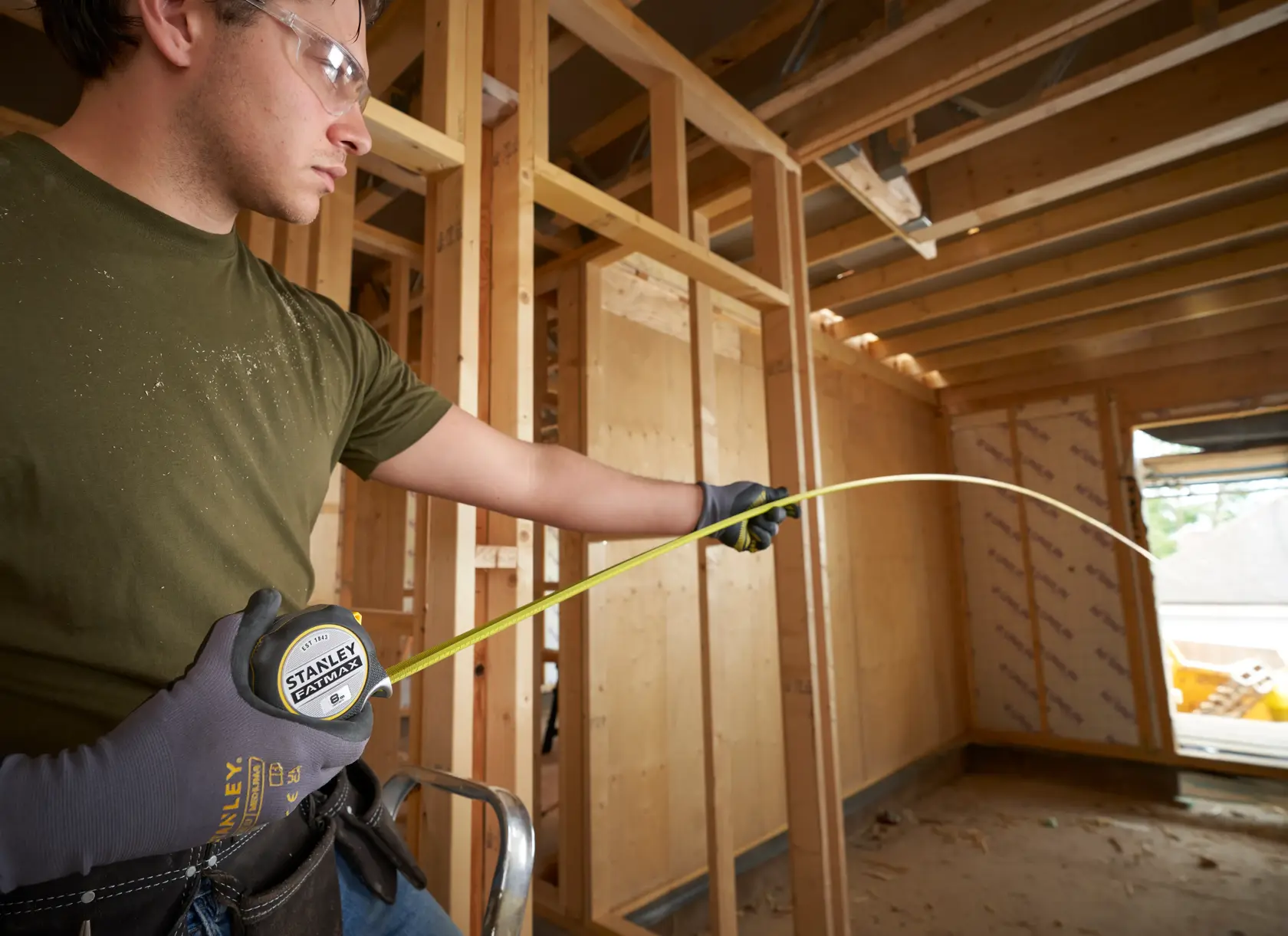 Photo of STANLEY FMHT38219-3 tape measure being used by a person wearing gloves at a construction site.
