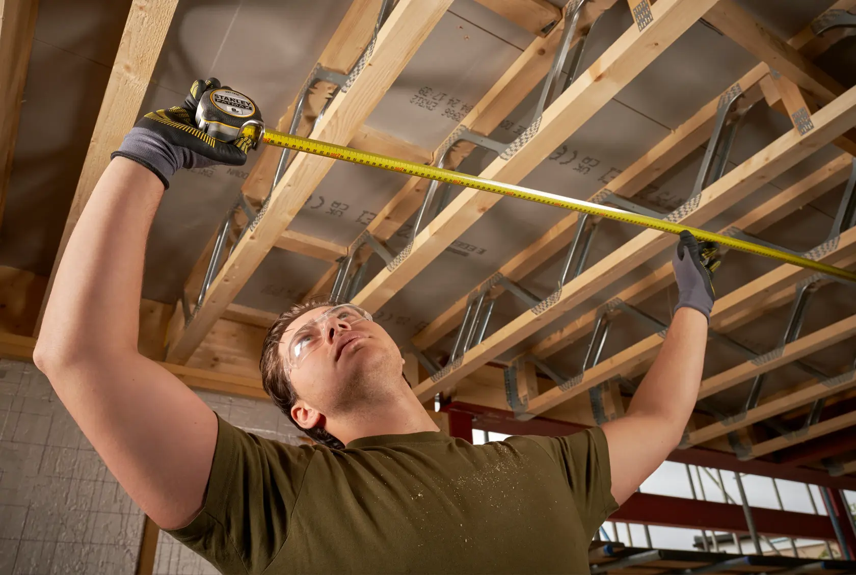 STANLEY FMHT38219-3 tape measure used by a person measuring ceiling joists, photography of product in use.