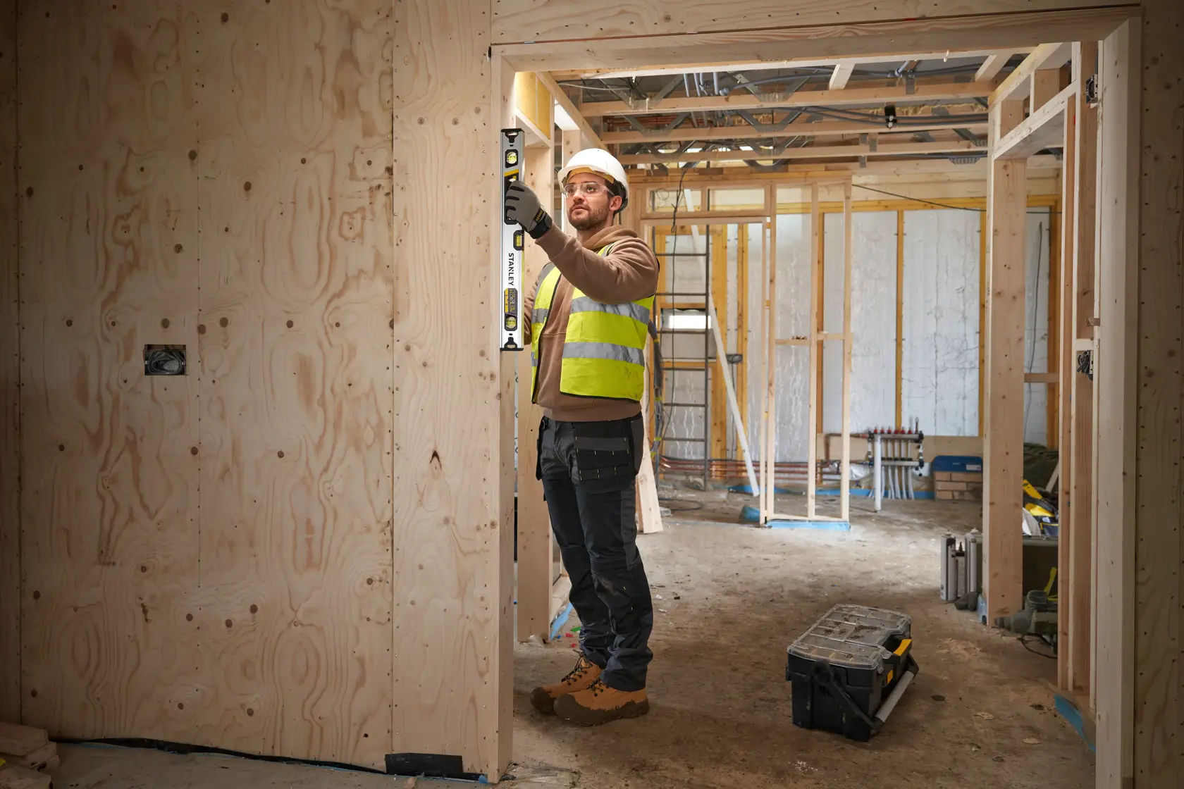 STANLEY FMHT43673-1 spirit level used by worker on wooden door frame at construction site.