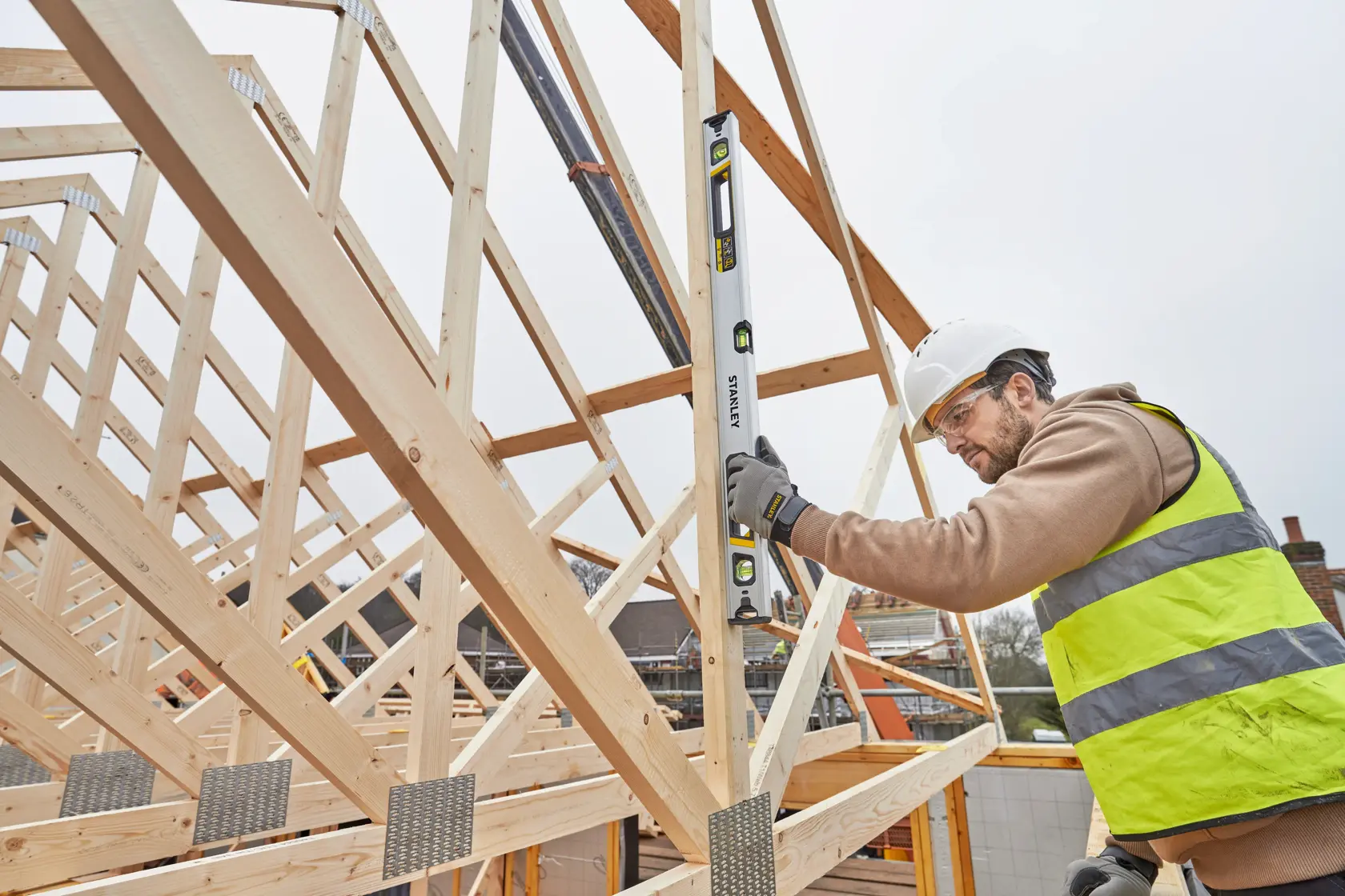 STANLEY FMHT43674-1 spirit level used by worker on timber roof frame at construction site.