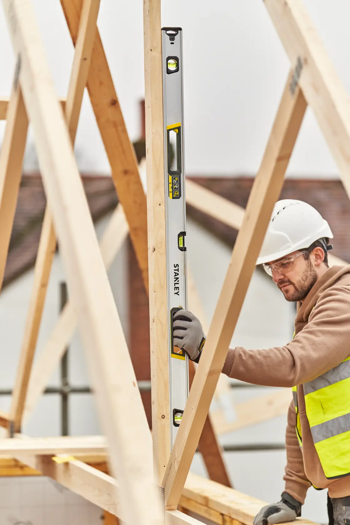 STANLEY FMHT43676-1 spirit level in use by a construction worker on a wooden frame building site.