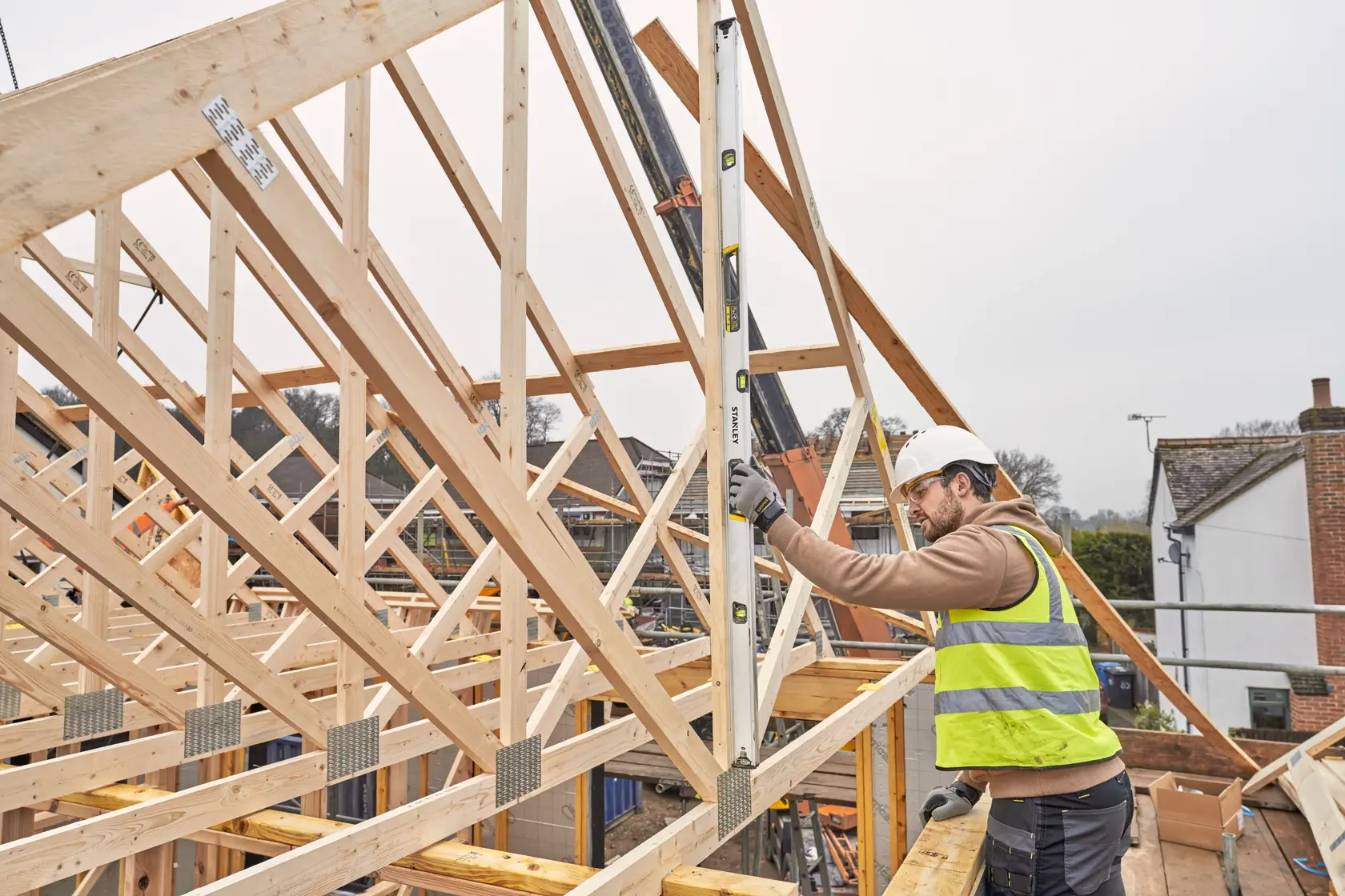 STANLEY FMHT43678-1 spirit level used by a construction worker on a timber roof frame, outdoor jobsite.