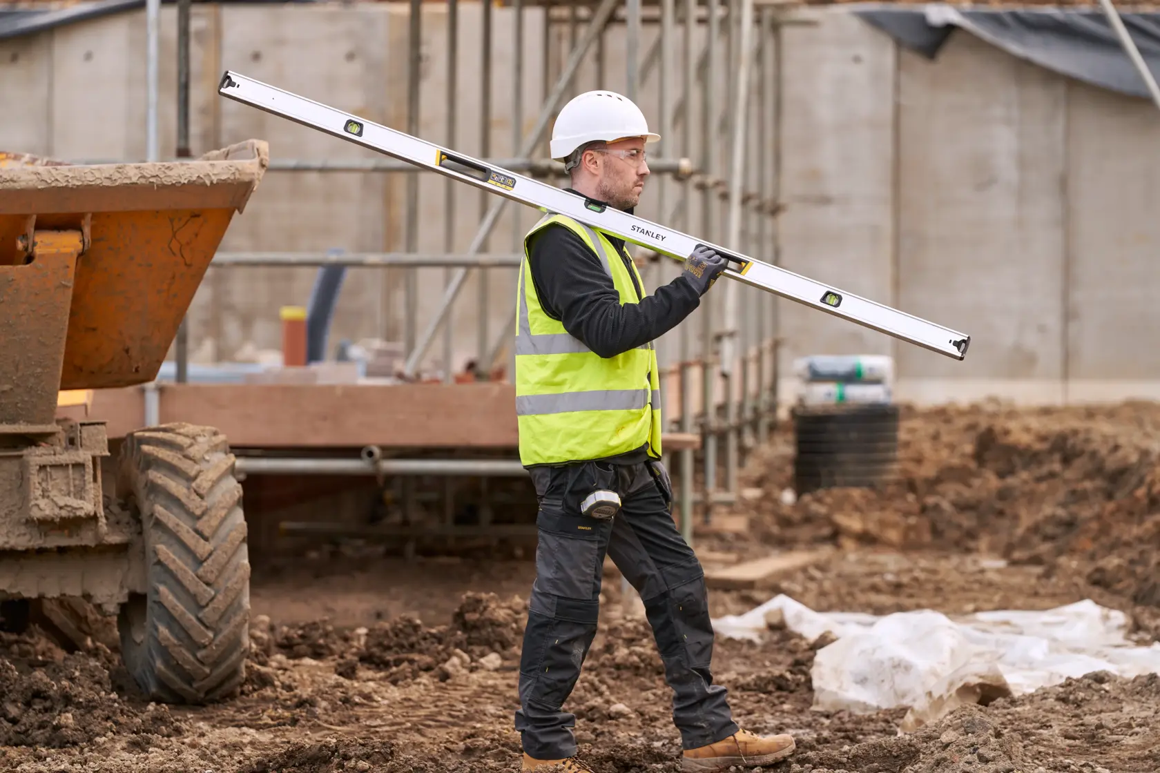 STANLEY FMHT43680-1 spirit level carried by construction worker in safety gear at building site.