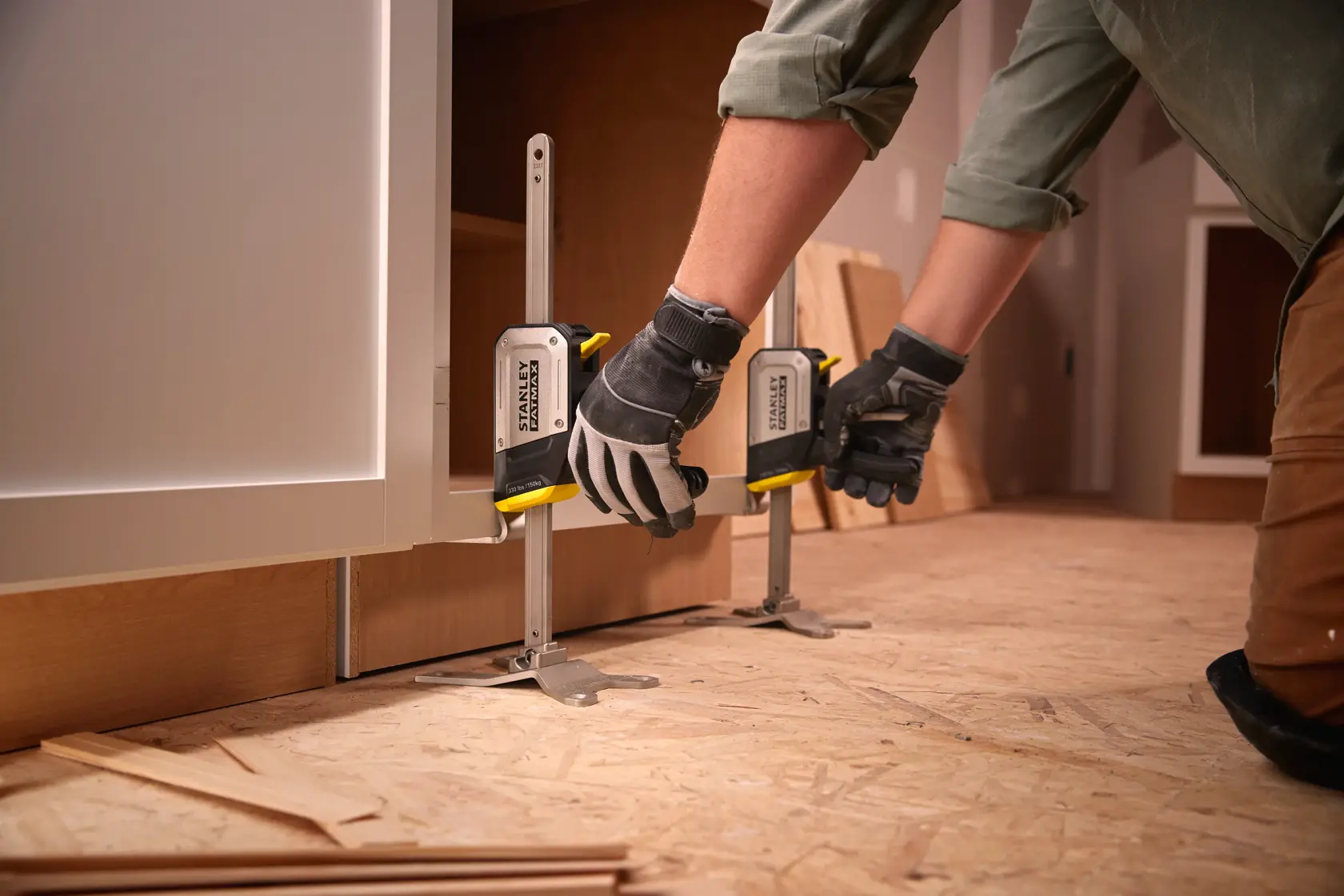 Stanley FMHT83550-1 cabinet clamp photography, worker adjusting clamps on wooden cabinet base.