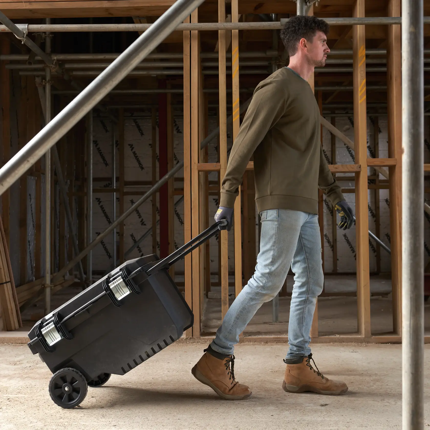 STANLEY FMST1-73601 rolling tool box with handle being pulled on a construction site.