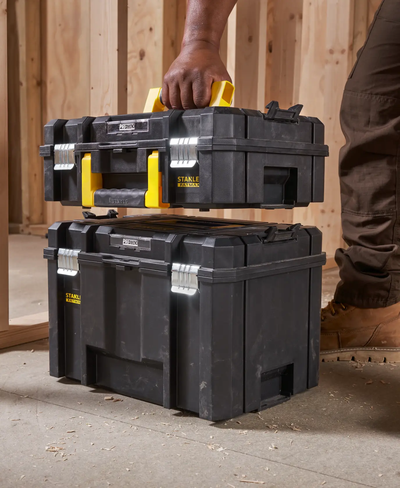 STANLEY FMST1-75502 tool box with yellow handle, shown being carried and stacked in a workshop setting.