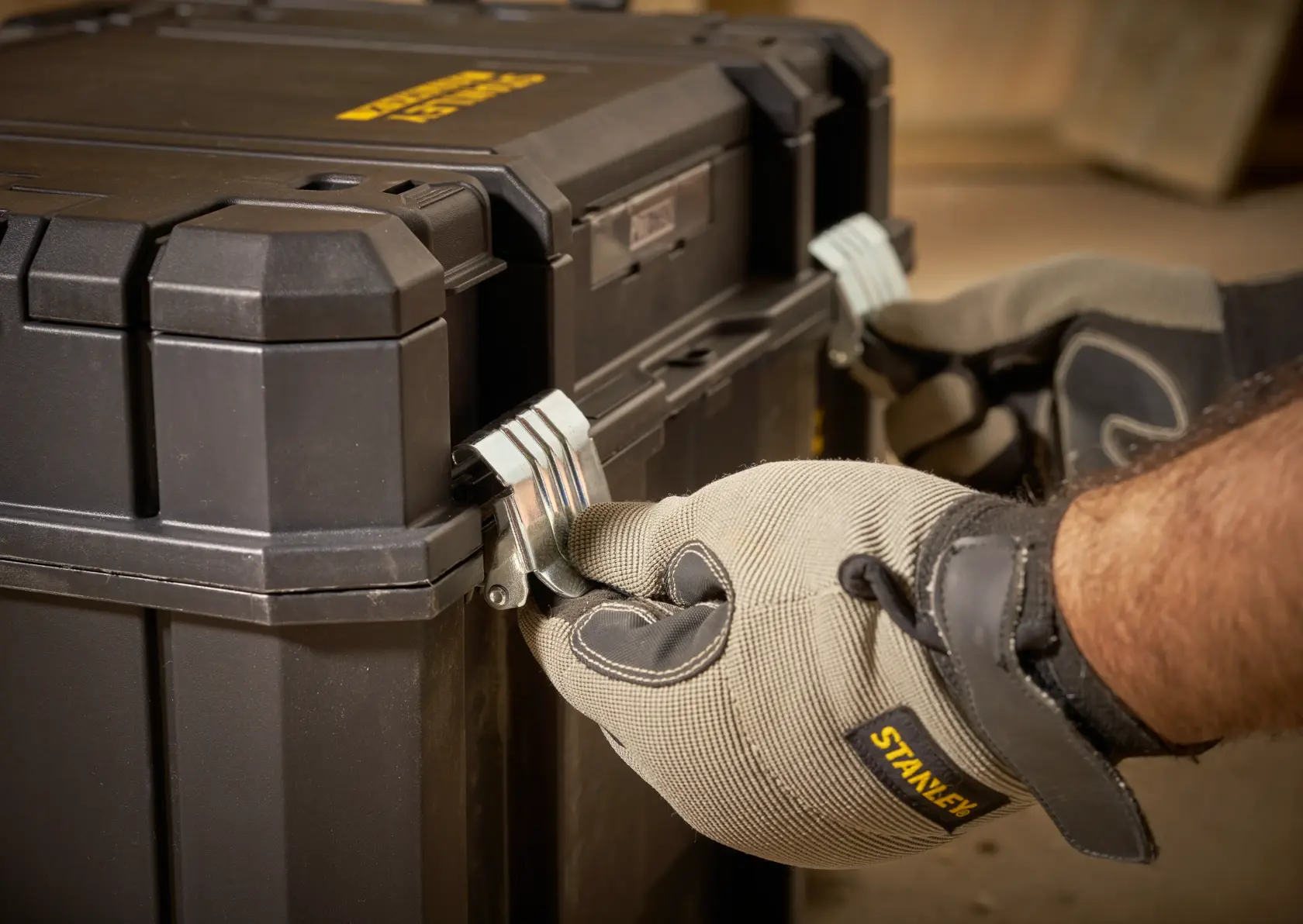 STANLEY FMST1-75796 toolbox close-up, gloved hands locking metal latches, product photography.
