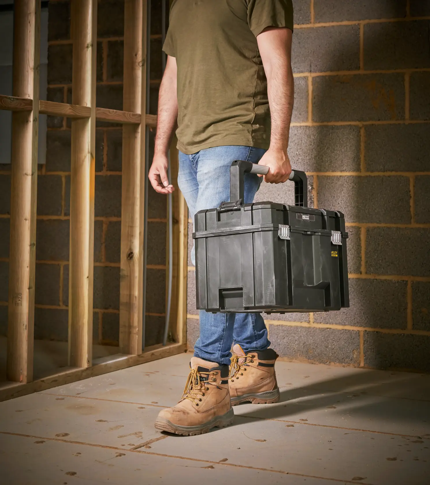 STANLEY FMST1-75796 black toolbox carried by person on construction site, product category photography.