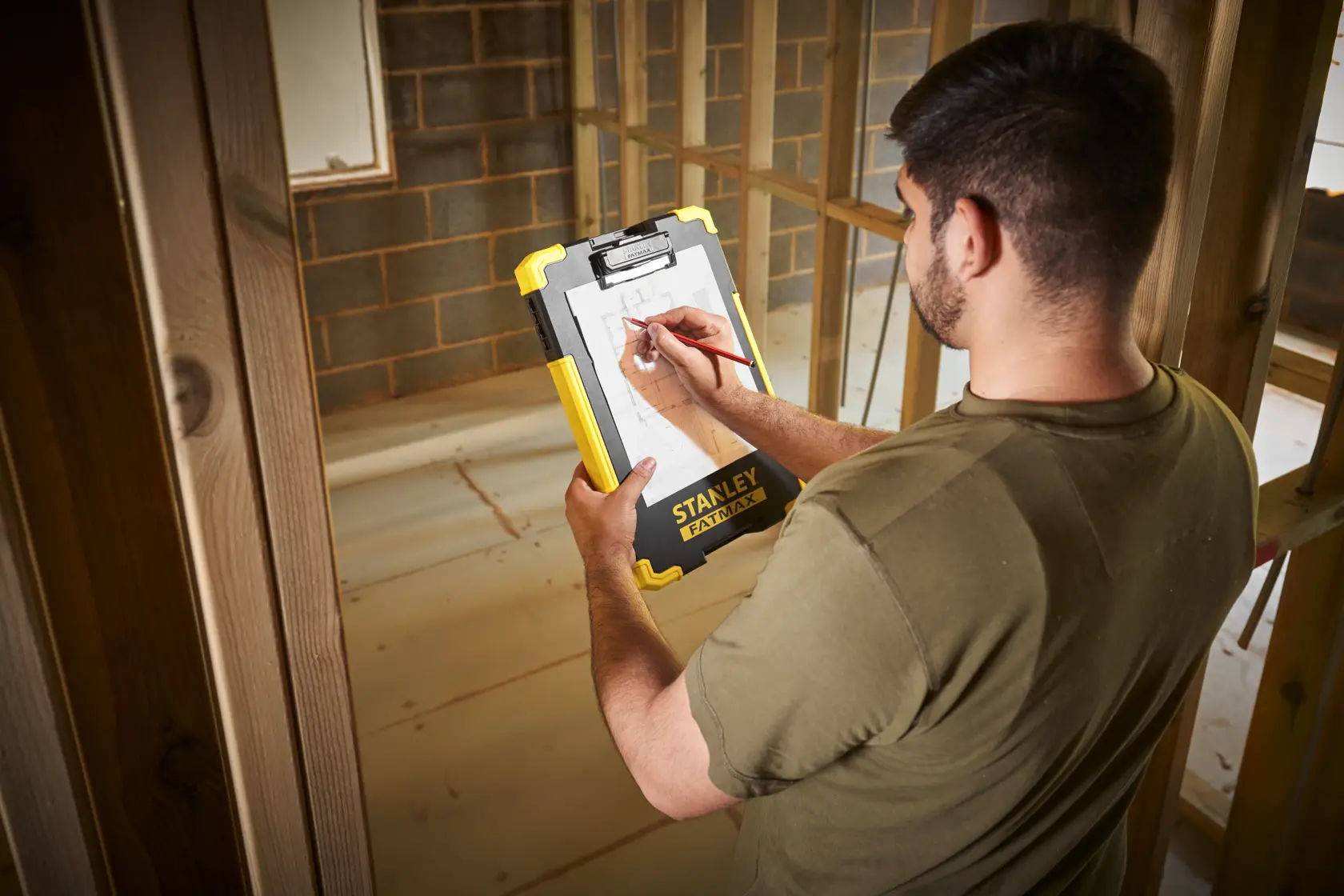 Photo of STANLEY FMST82721-1 clipboard held on construction site, showing yellow and black durable design.