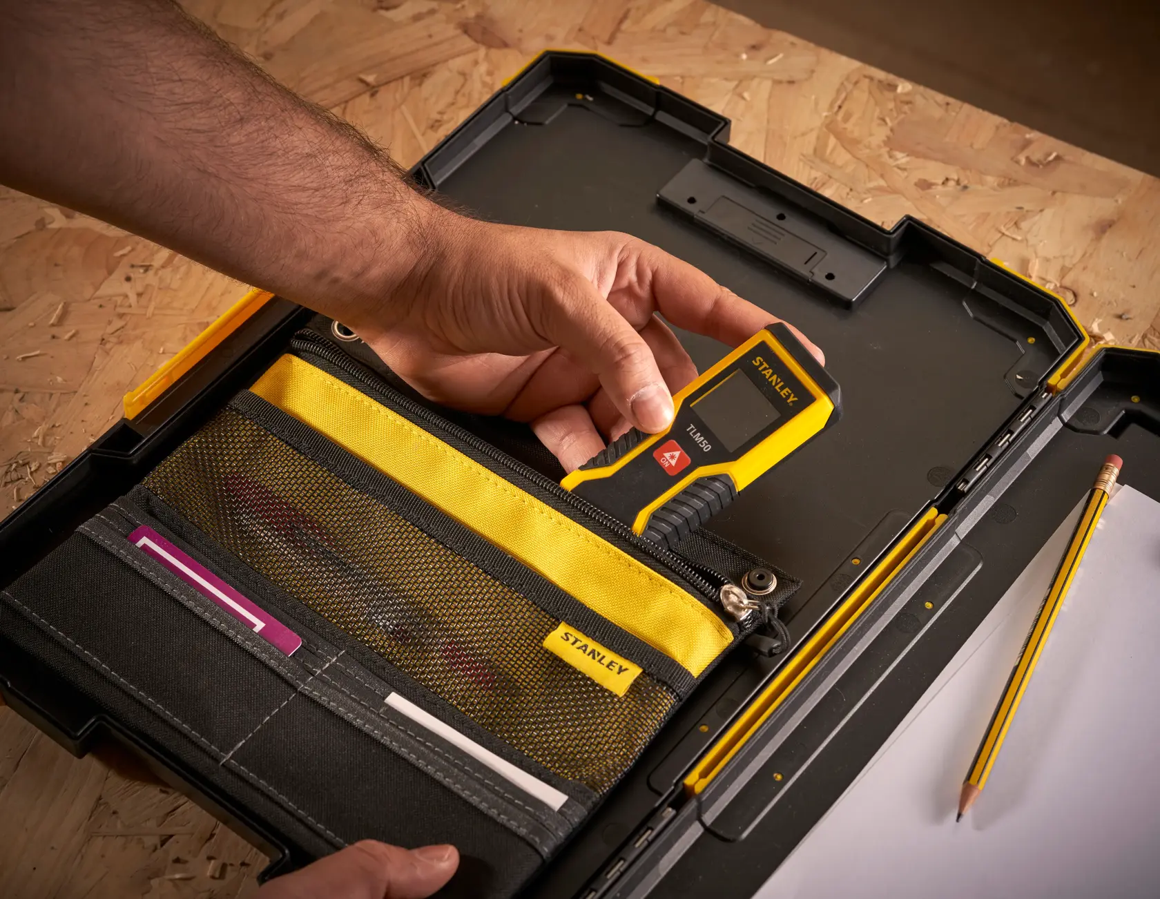 Photo of STANLEY FMST82721-1 tool case with yellow and black organizer, hand holding digital measuring tool.