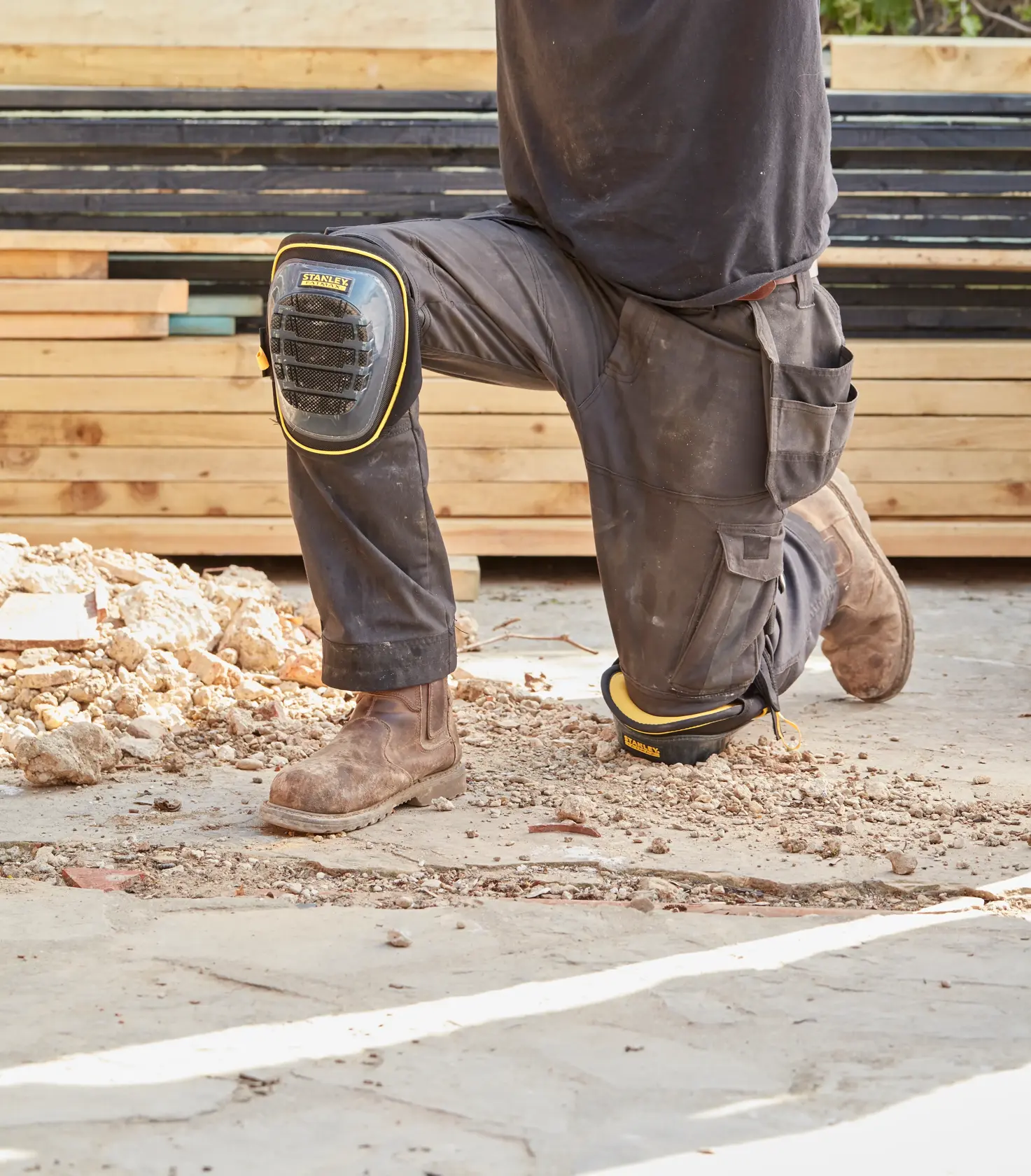 STANLEY FMST82960-1 work knee pads worn on site, black with yellow trim, durable shell design.
