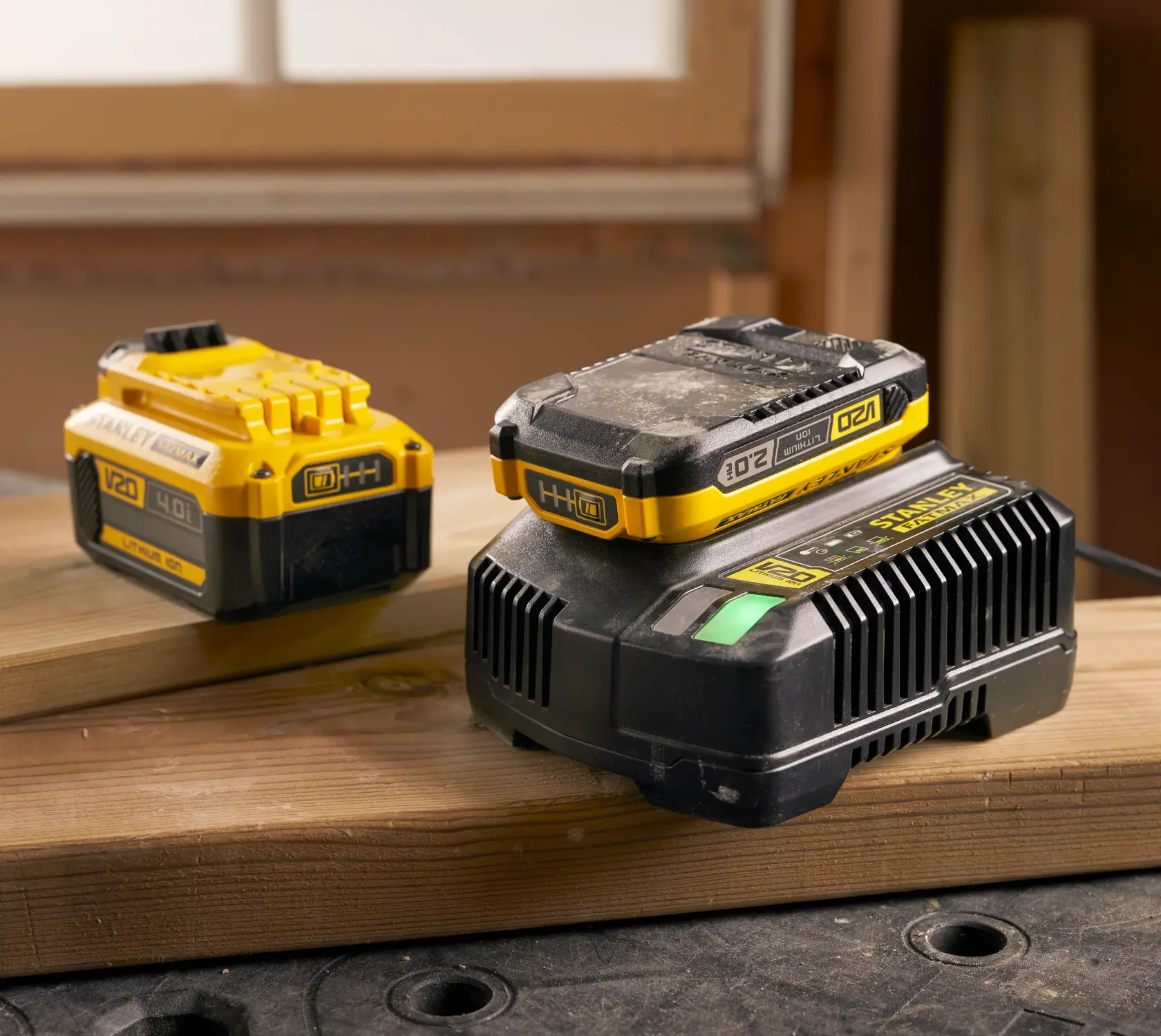 Photo of STANLEY SFMCB14 V20 lithium-ion battery and charger on wood, workshop background.