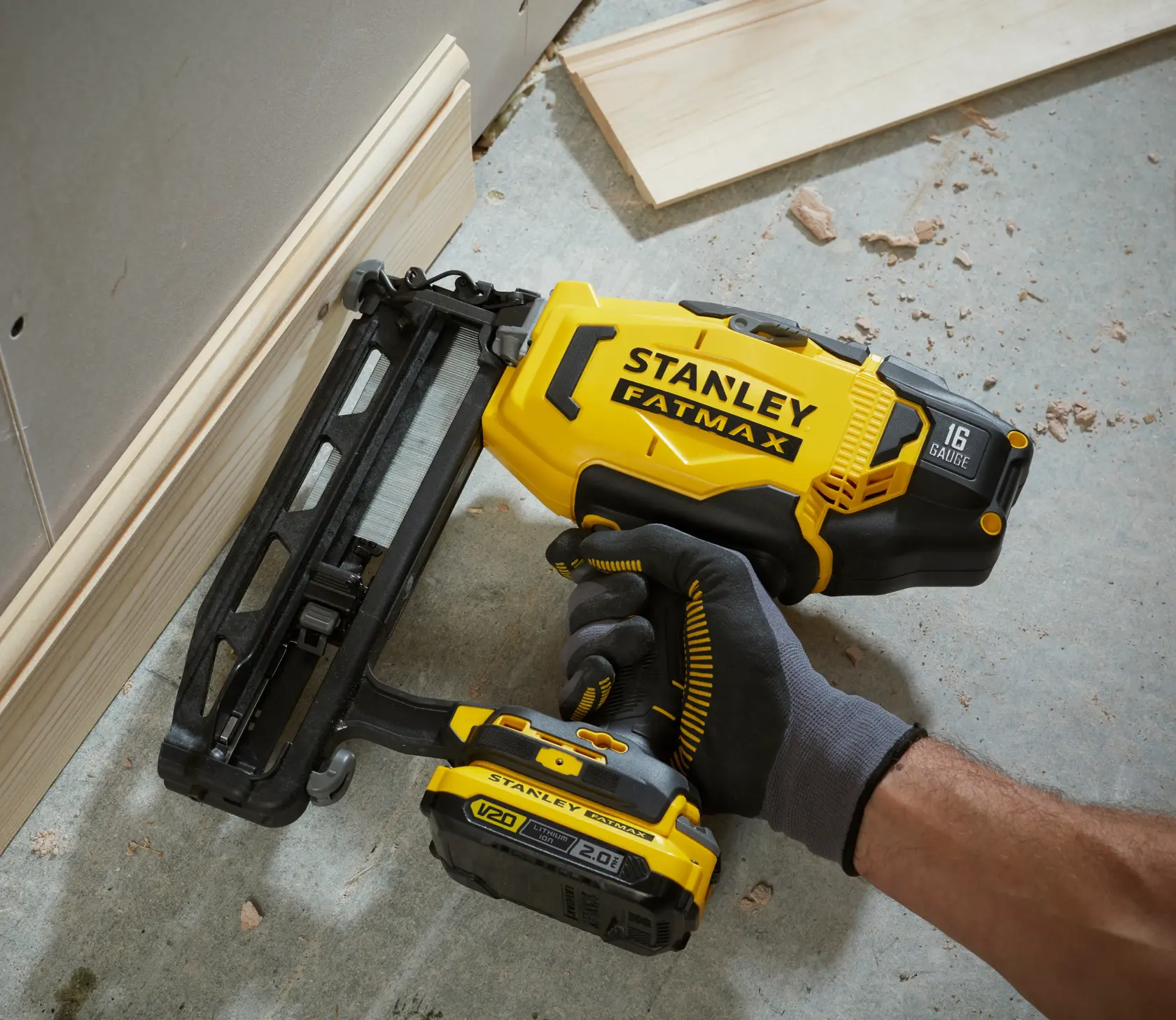 Photo of STANLEY SFMCB202 cordless nail gun in use on trim, yellow and black, side angle.