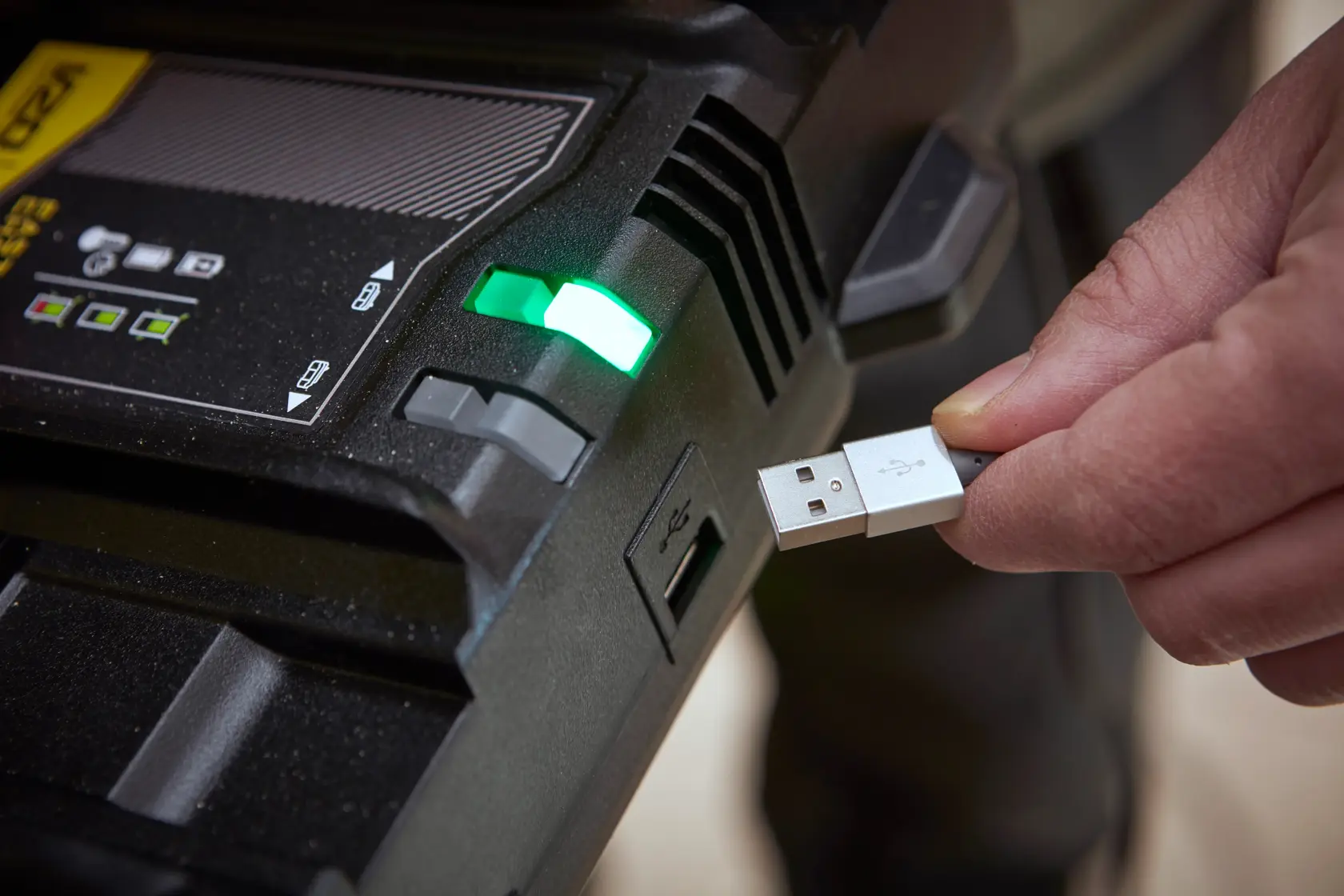 STANLEY SFMCB24 battery charger with green indicator and person plugging in USB cable, close-up.