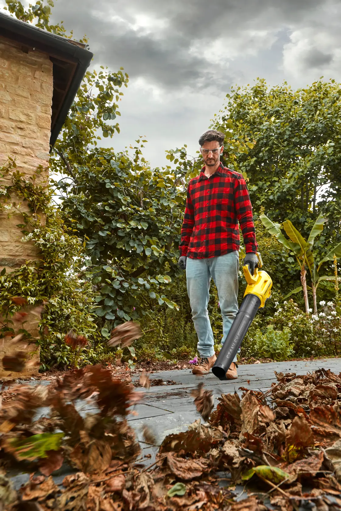Photo of STANLEY SFMCBL7B leaf blower in use outdoors, blowing dry leaves on a patio.