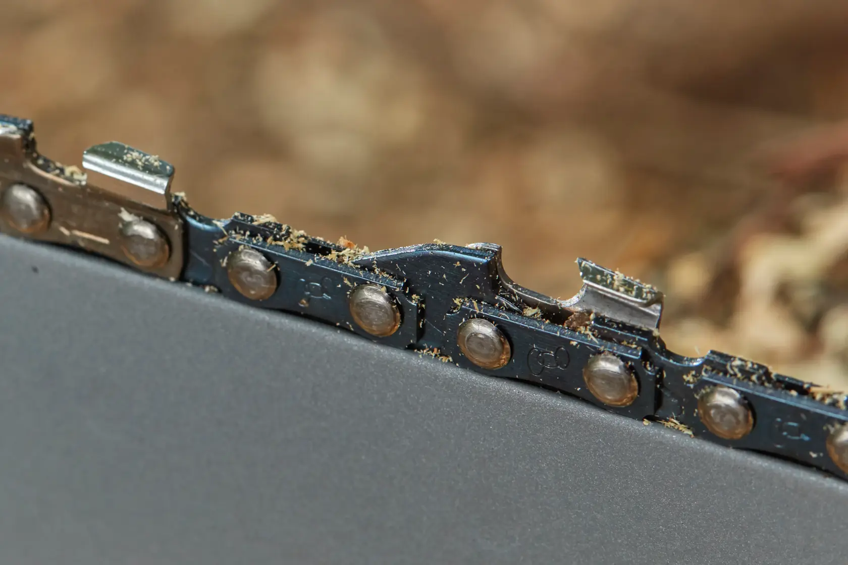 STANLEY SFMCCS630B chainsaw close-up, showing metal chain teeth and cutting edges with sawdust.