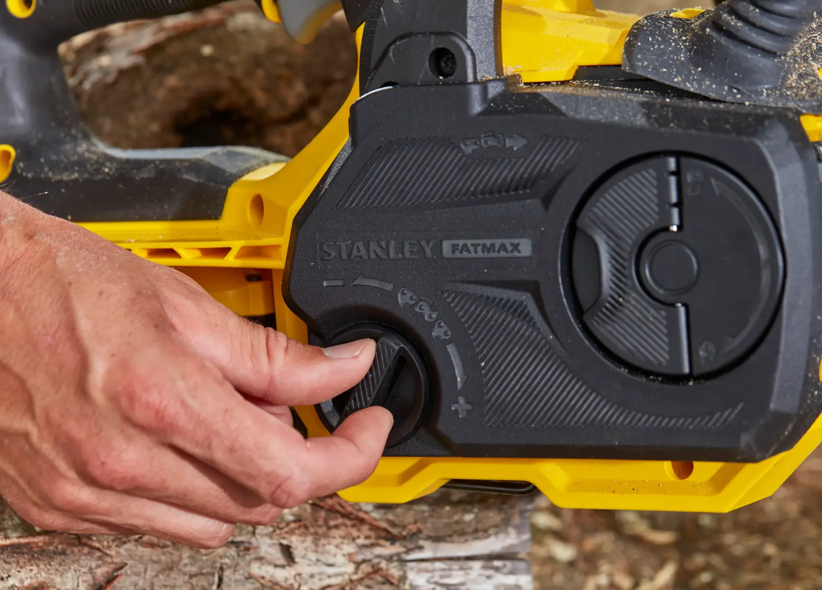 Photo of STANLEY SFMCCS630M1 chainsaw control panel with hand adjusting knob, close-up angle.
