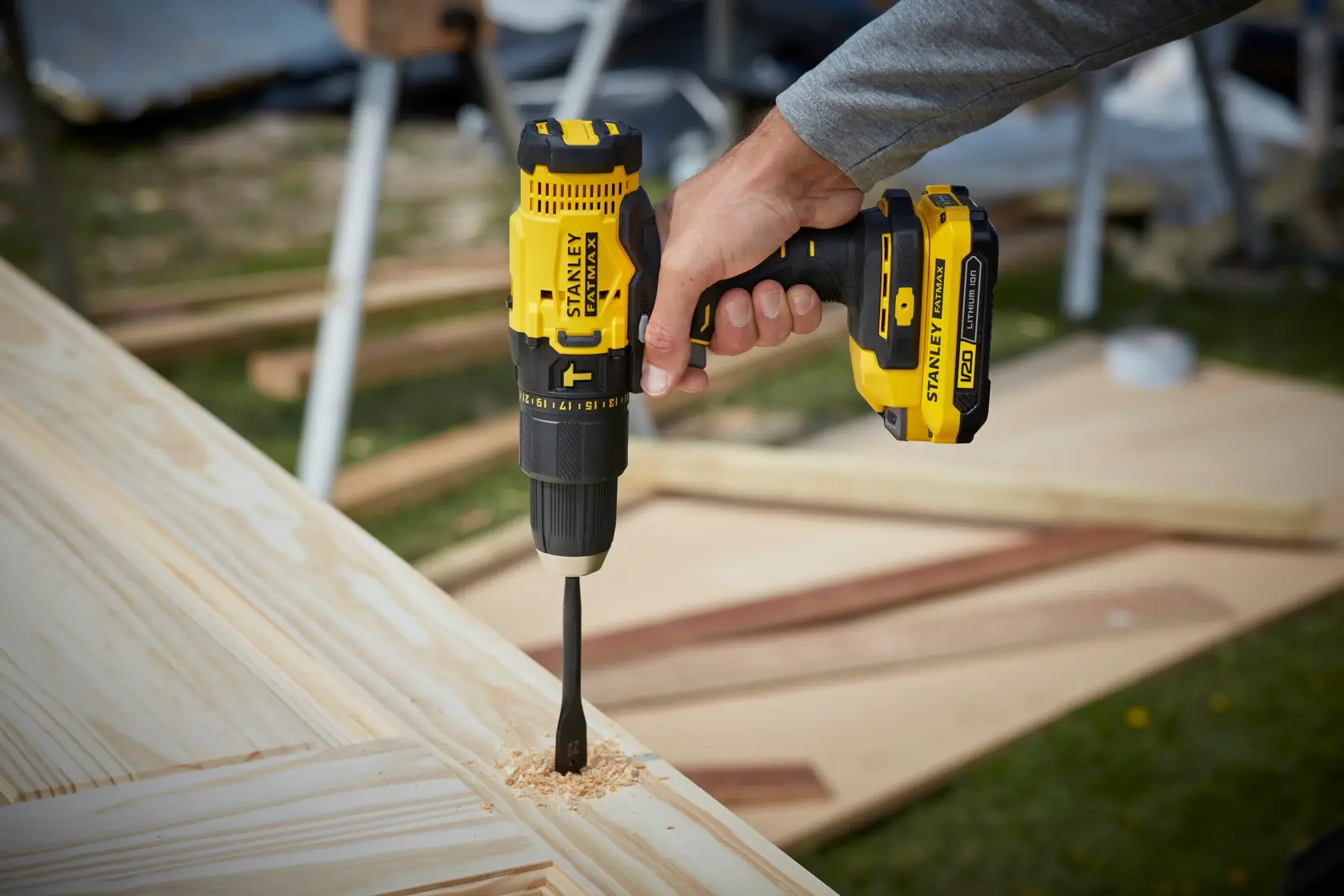 STANLEY SFMCD711B cordless drill being used on wood, close-up showing yellow and black tool.