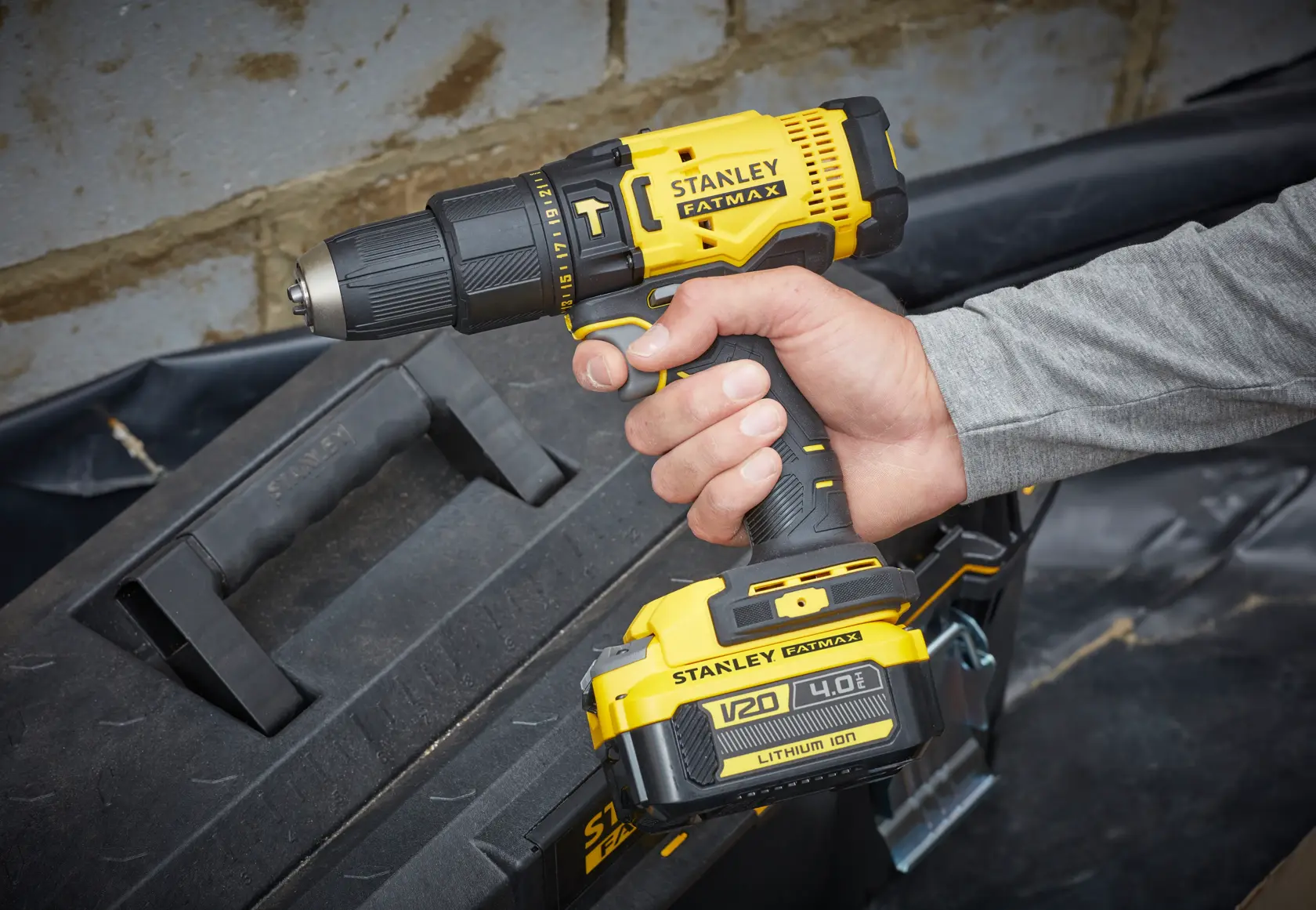 Photo of STANLEY SFMCD711M1 cordless drill driver held in hand, shown near a black tool box.