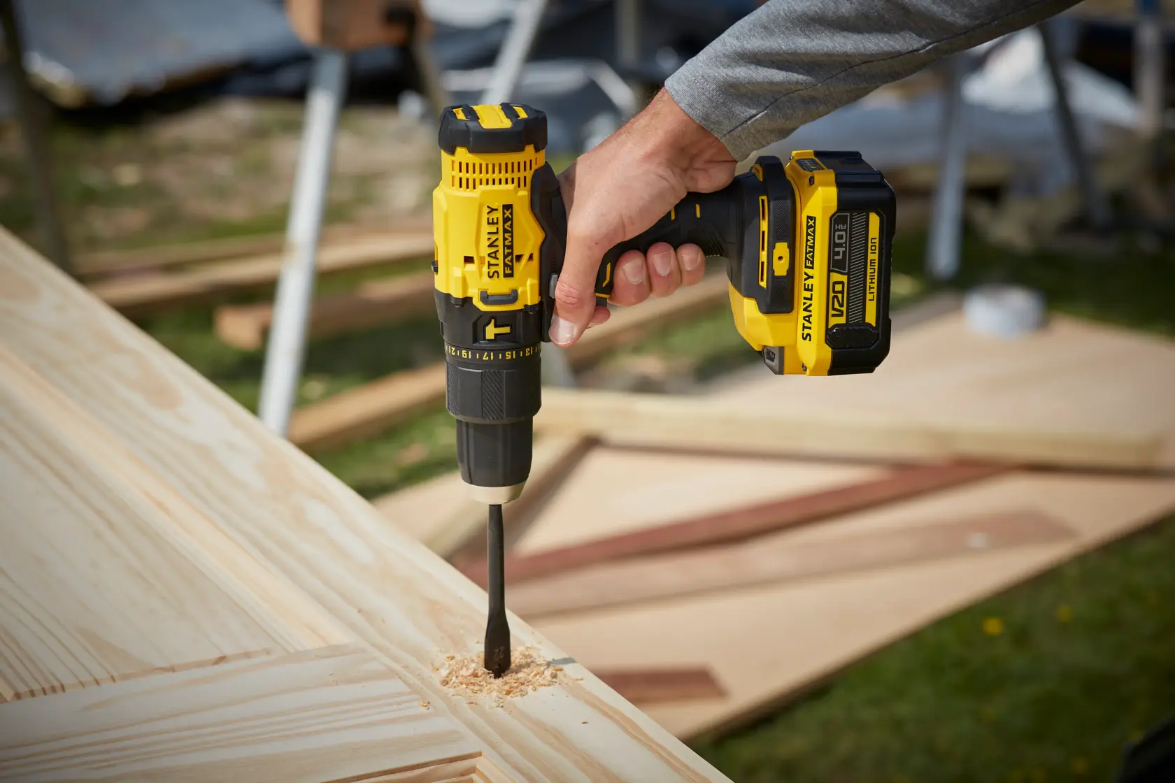 STANLEY SFMCD711M1 cordless drill in use, drilling into light wood panel outdoors.
