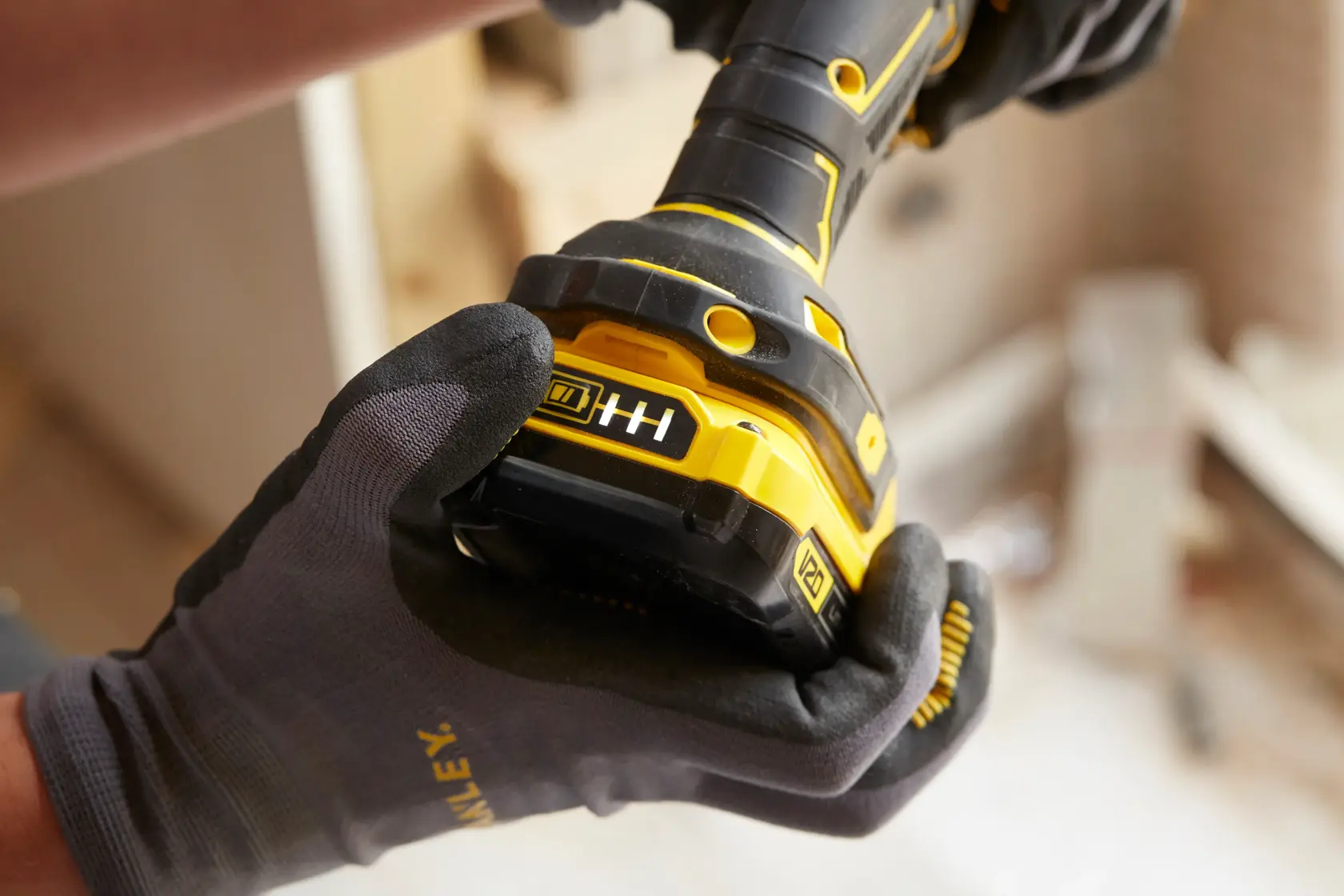 STANLEY SFMCD720B cordless drill close-up held by gloved hand, yellow and black body visible.