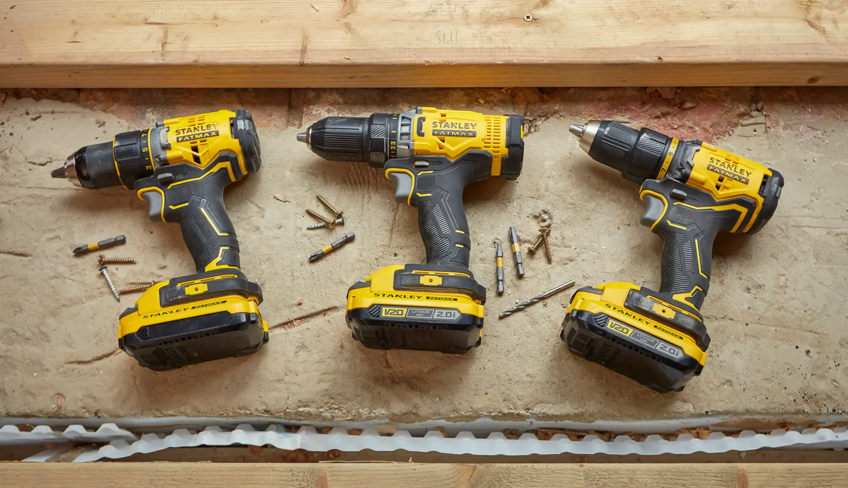 STANLEY SFMCD720B cordless drills in yellow and black, top view on concrete with bits and screws.