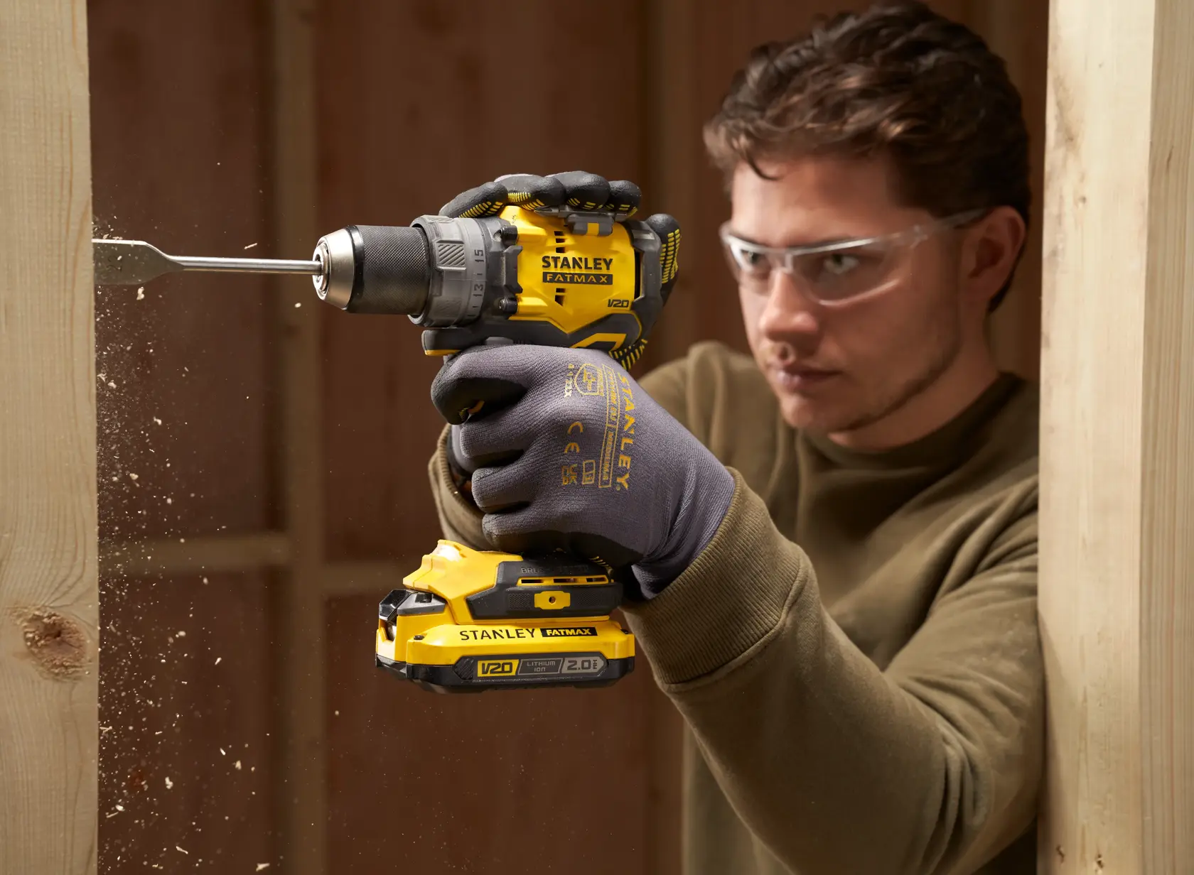 Photo of STANLEY SFMCD725D2K cordless drill in use drilling through wood, close-up view.