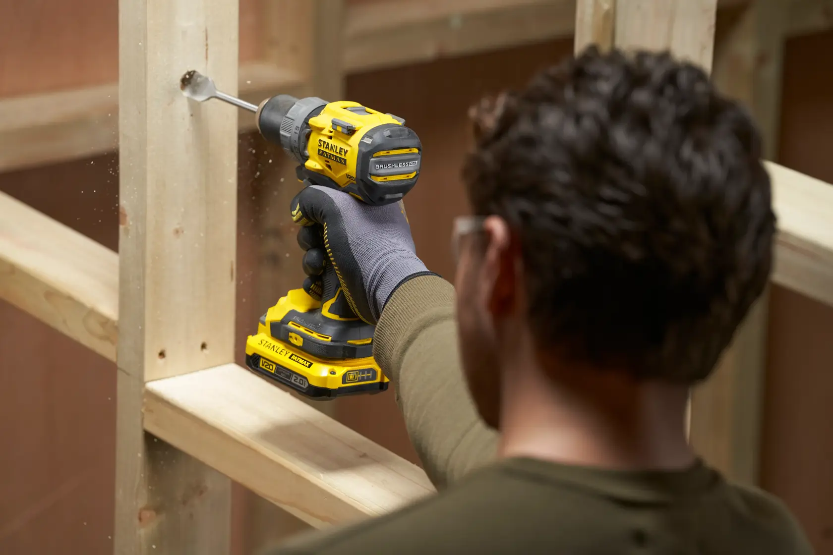 STANLEY SFMCD725D2K cordless drill in use drilling wood, construction setting, side angle.