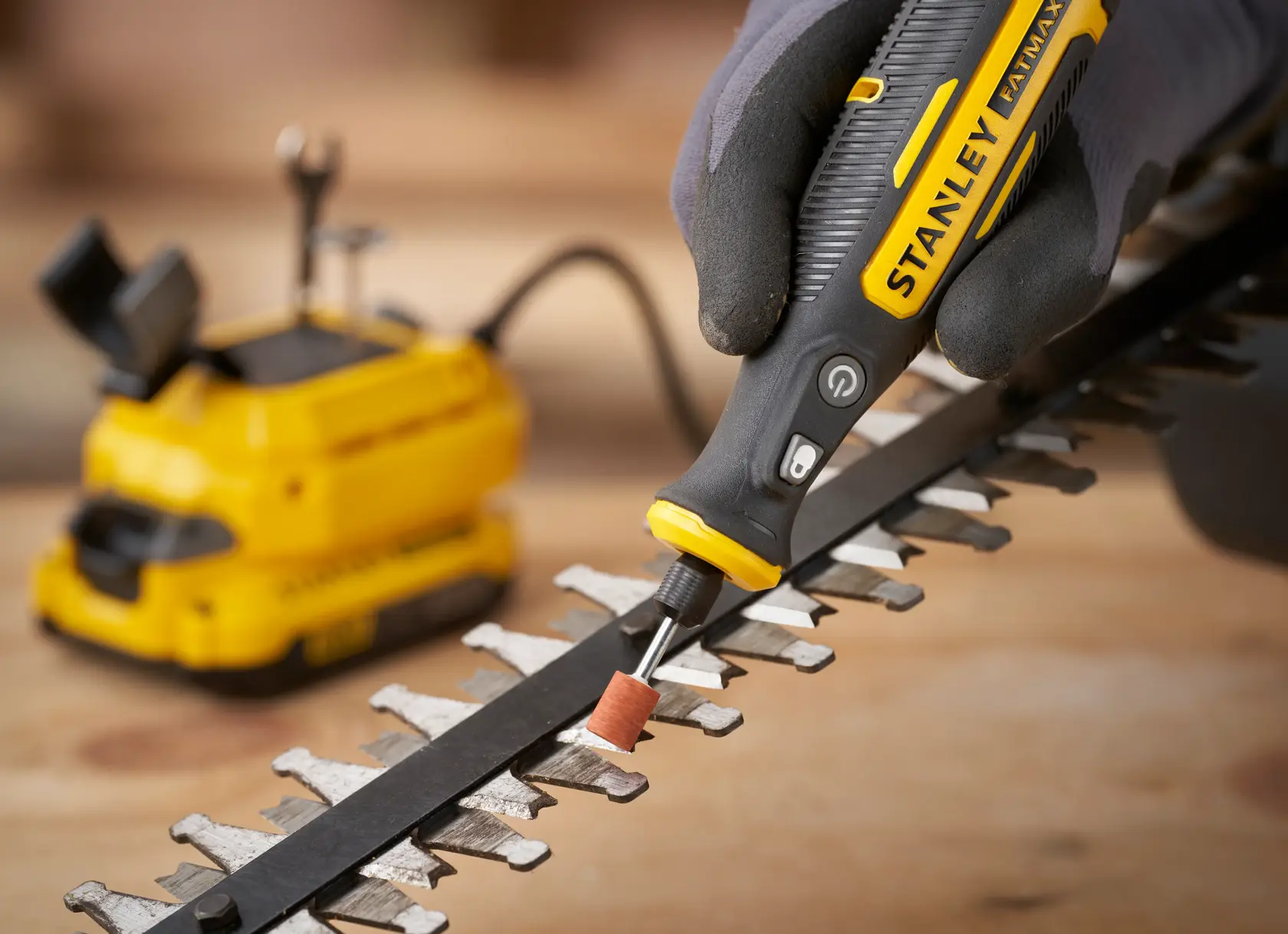 STANLEY SFMCE030B rotary tool used to grind metal blade, close-up angle, yellow and black design.