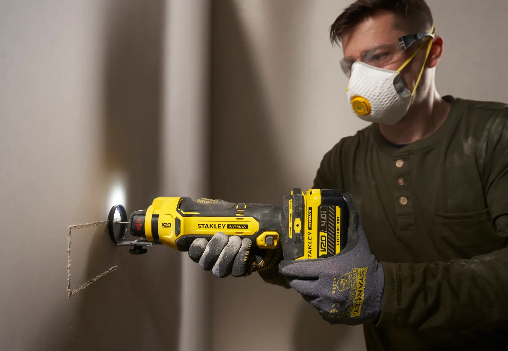 STANLEY SFMCE200B oscillating multi-tool cutting drywall, close-up side angle view.