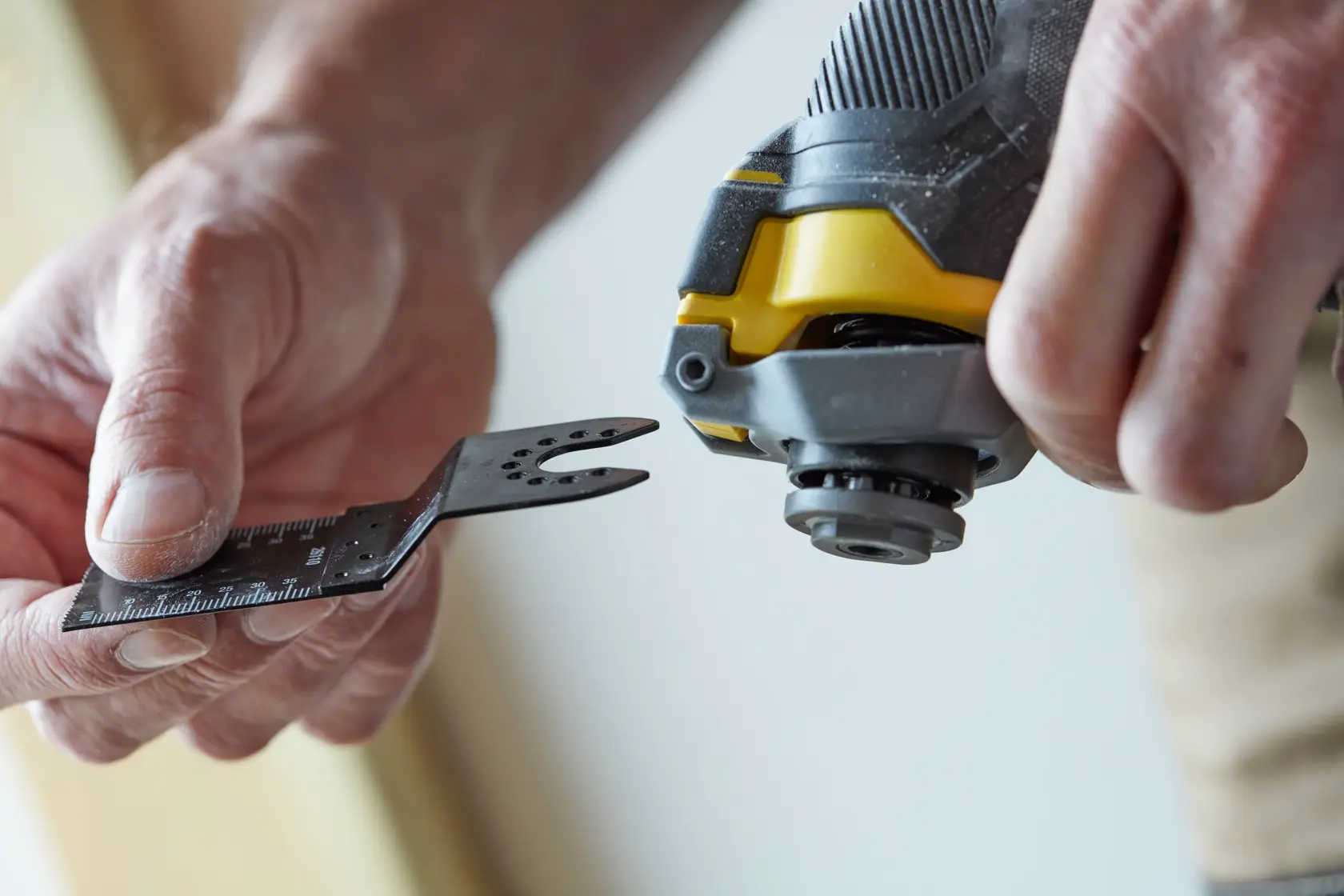 STANLEY SFMCE500B oscillating multi-tool close-up, hand attaching blade accessory.