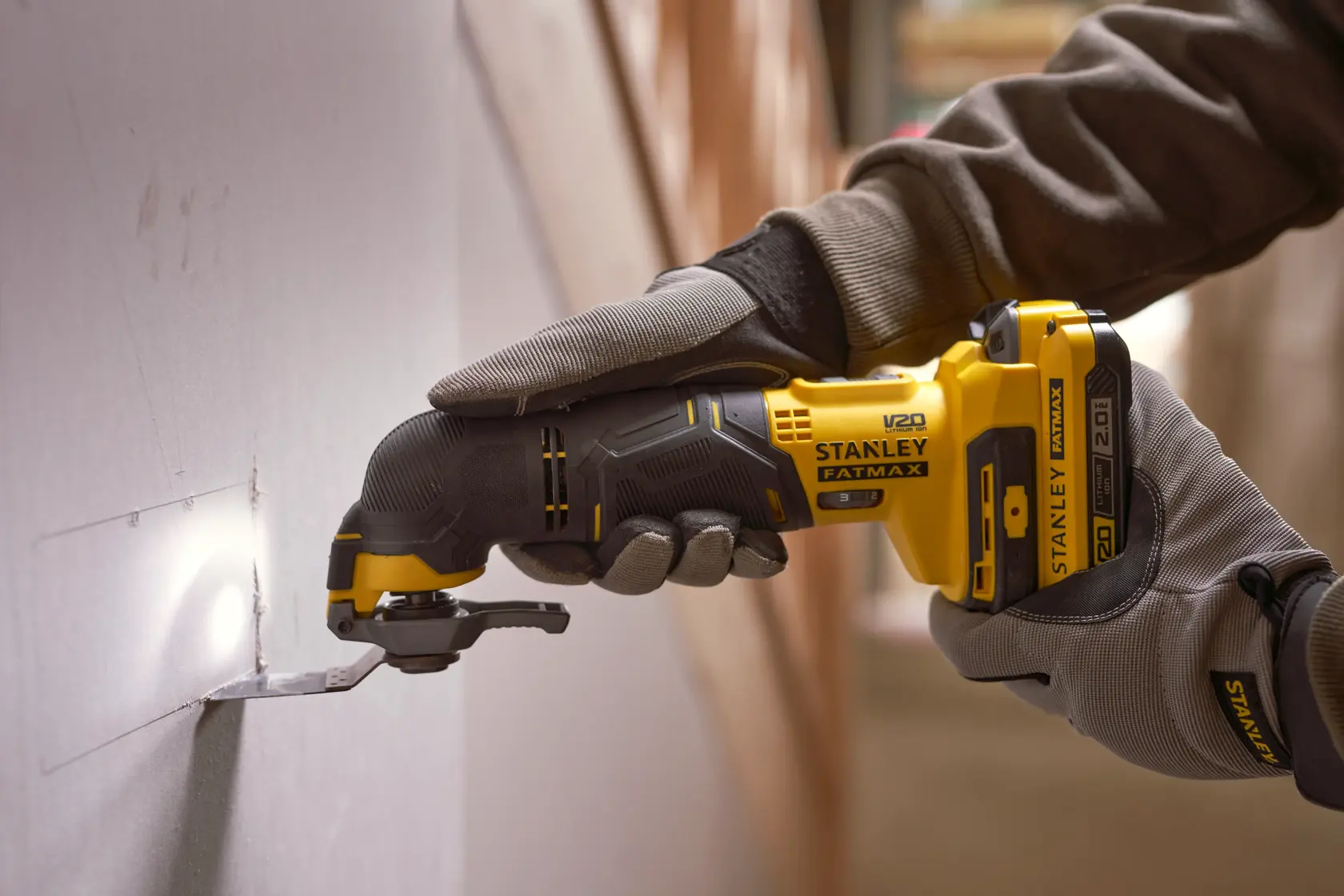 STANLEY SFMCE500D1K cordless oscillating multi-tool cutting drywall, close-up action shot.