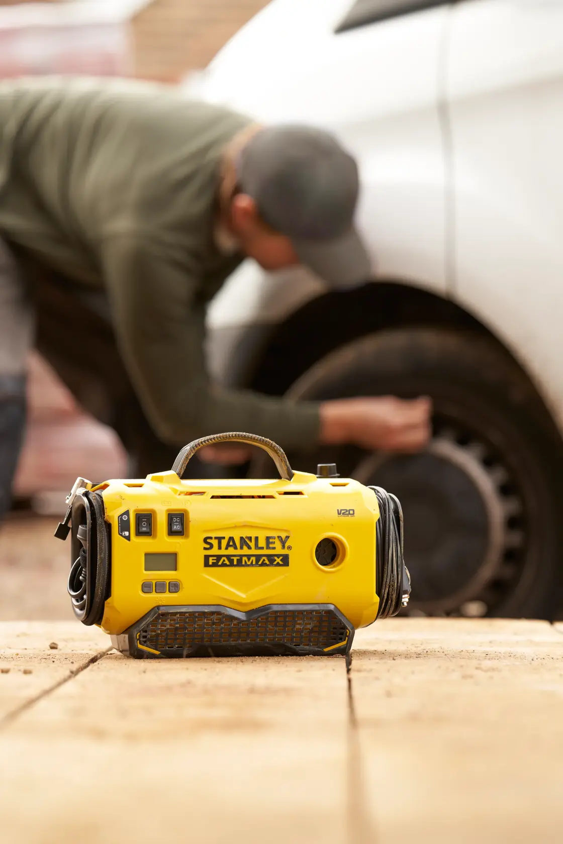 STANLEY SFMCE520B portable yellow FATMAX inflator shown outdoors, with person using it near a car tire.