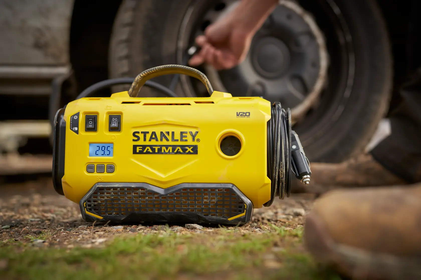 STANLEY SFMCE520B portable yellow tire inflator with digital display, shown outdoors near a car wheel.