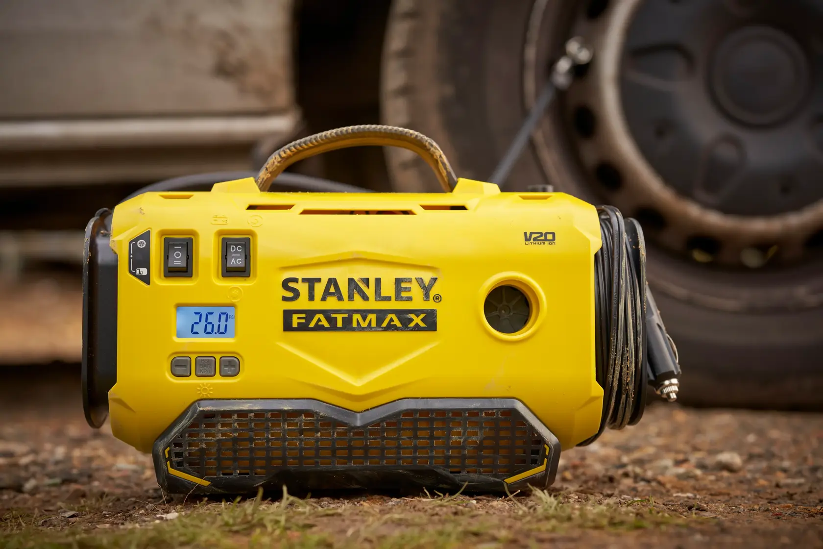 Photo of STANLEY SFMCE520B FATMAX portable tire inflator, yellow, showing digital display and hose, outdoor scene.