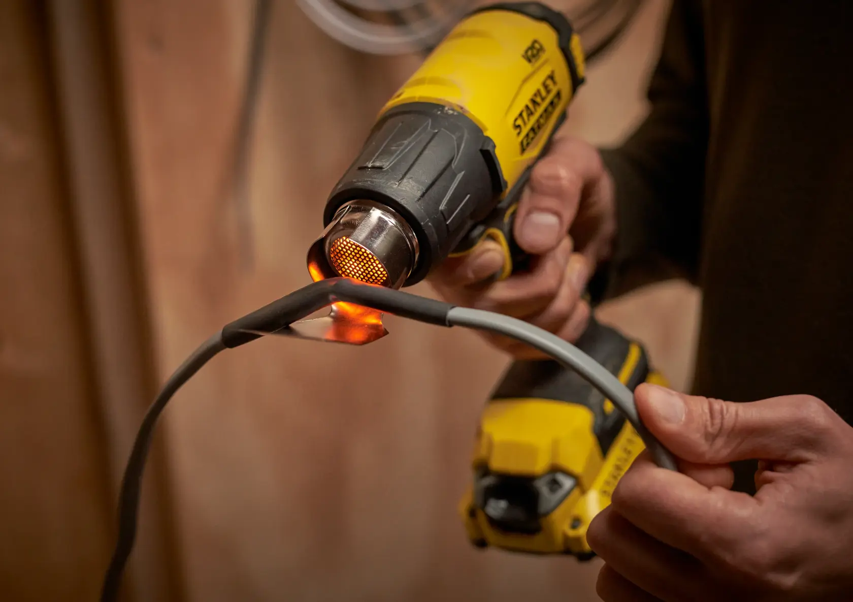 STANLEY SFMCE530B heat gun in use on a wire, close-up, photography product category.