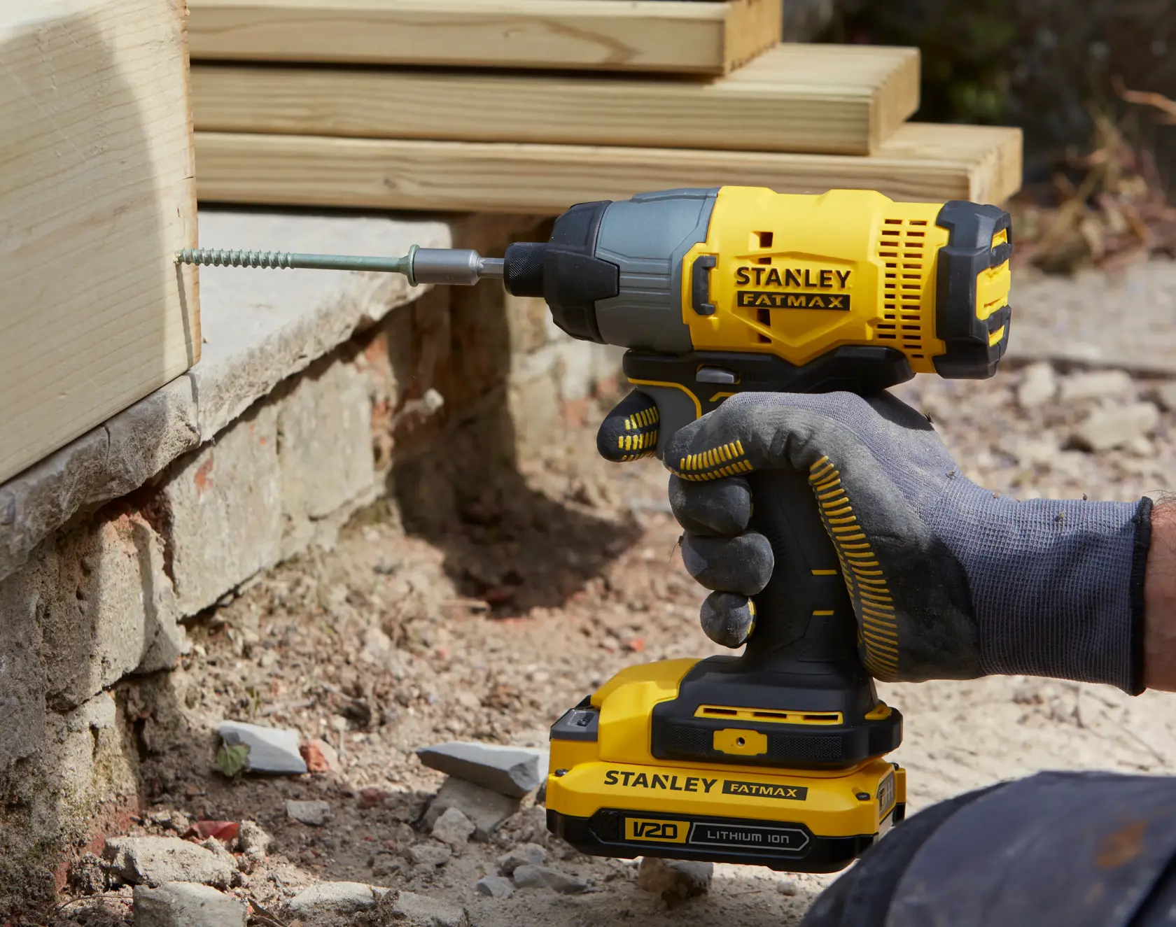 STANLEY SFMCF800DM2 impact driver in use, yellow and black, drilling screw into wooden beam.