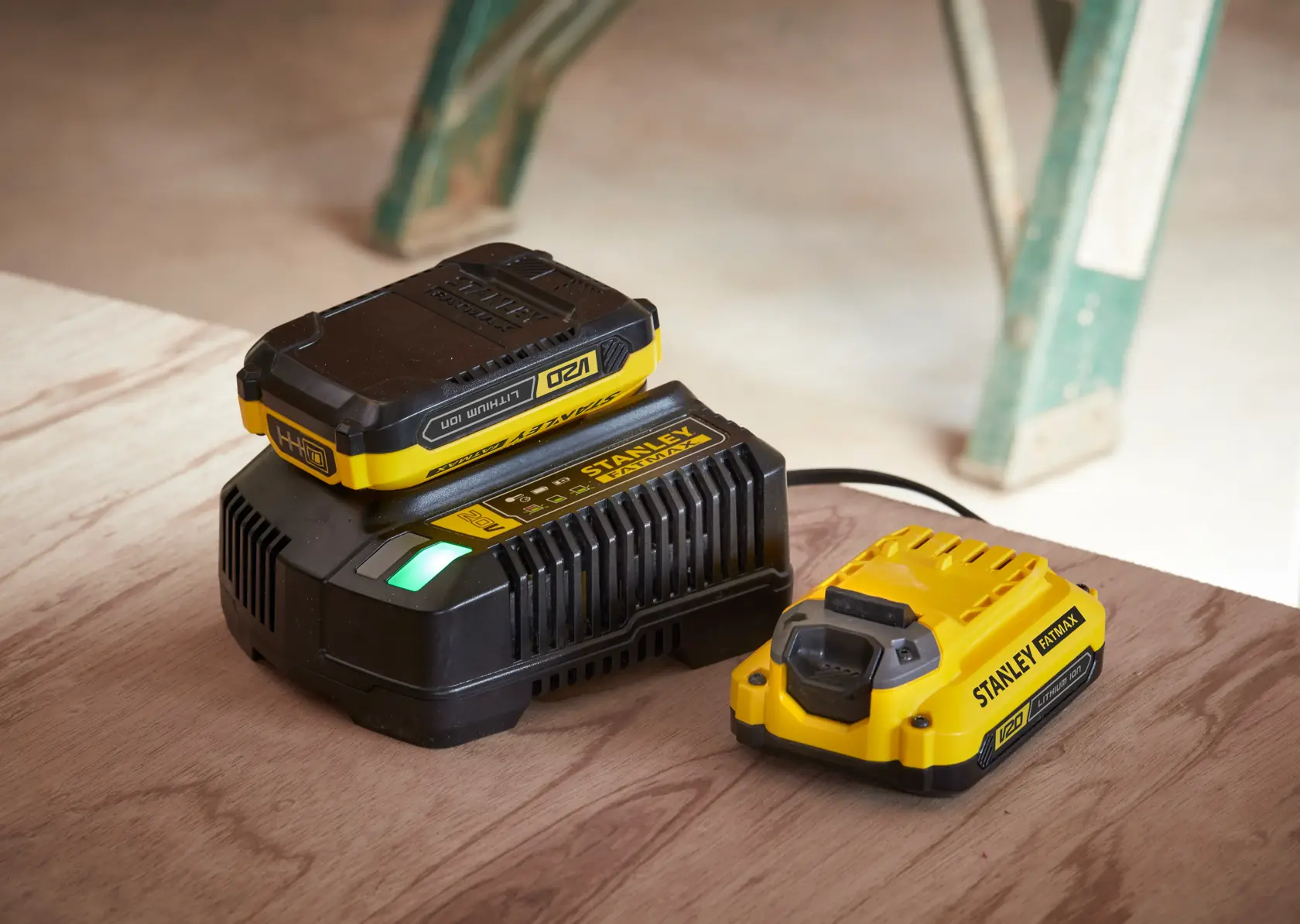 STANLEY SFMCF800DM2 battery charger and battery kit, yellow and black, side angle on wooden surface.