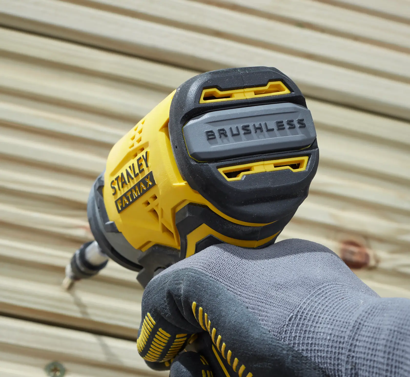 Photo of STANLEY SFMCF820B brushless impact driver held by gloved hand, close-up on back housing.