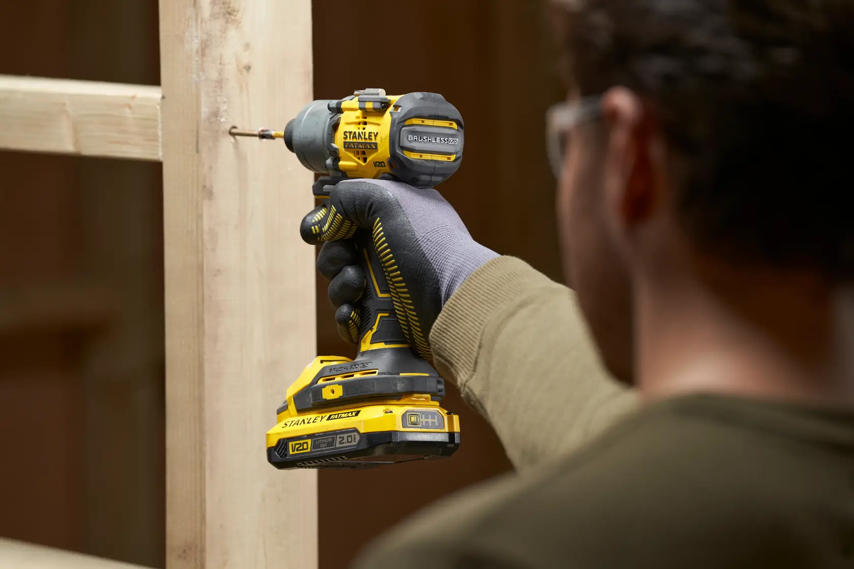Photo of STANLEY SFMCF830D2K cordless V20 impact driver being used to drive a screw into wood, close-up angle.