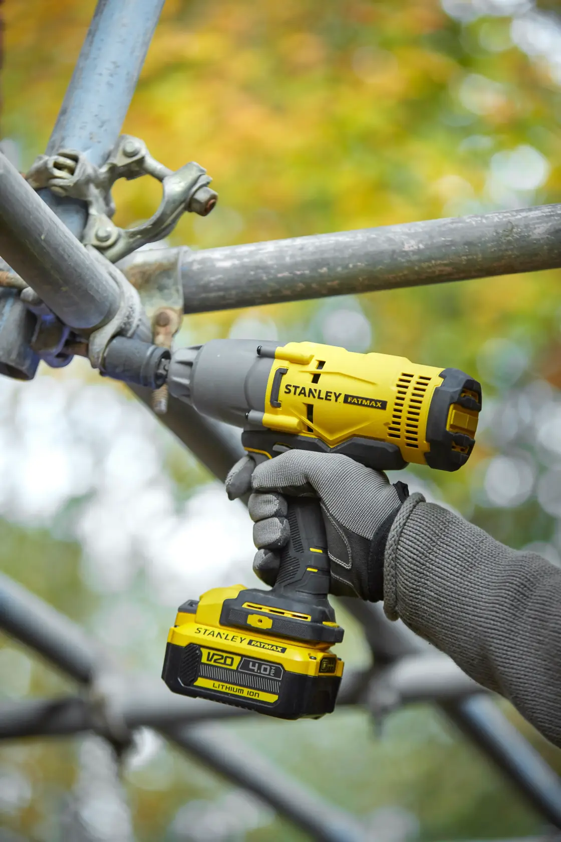 Photo of STANLEY SFMCF900B impact wrench used on scaffolding, yellow and black, V20 4.0Ah lithium-ion battery.