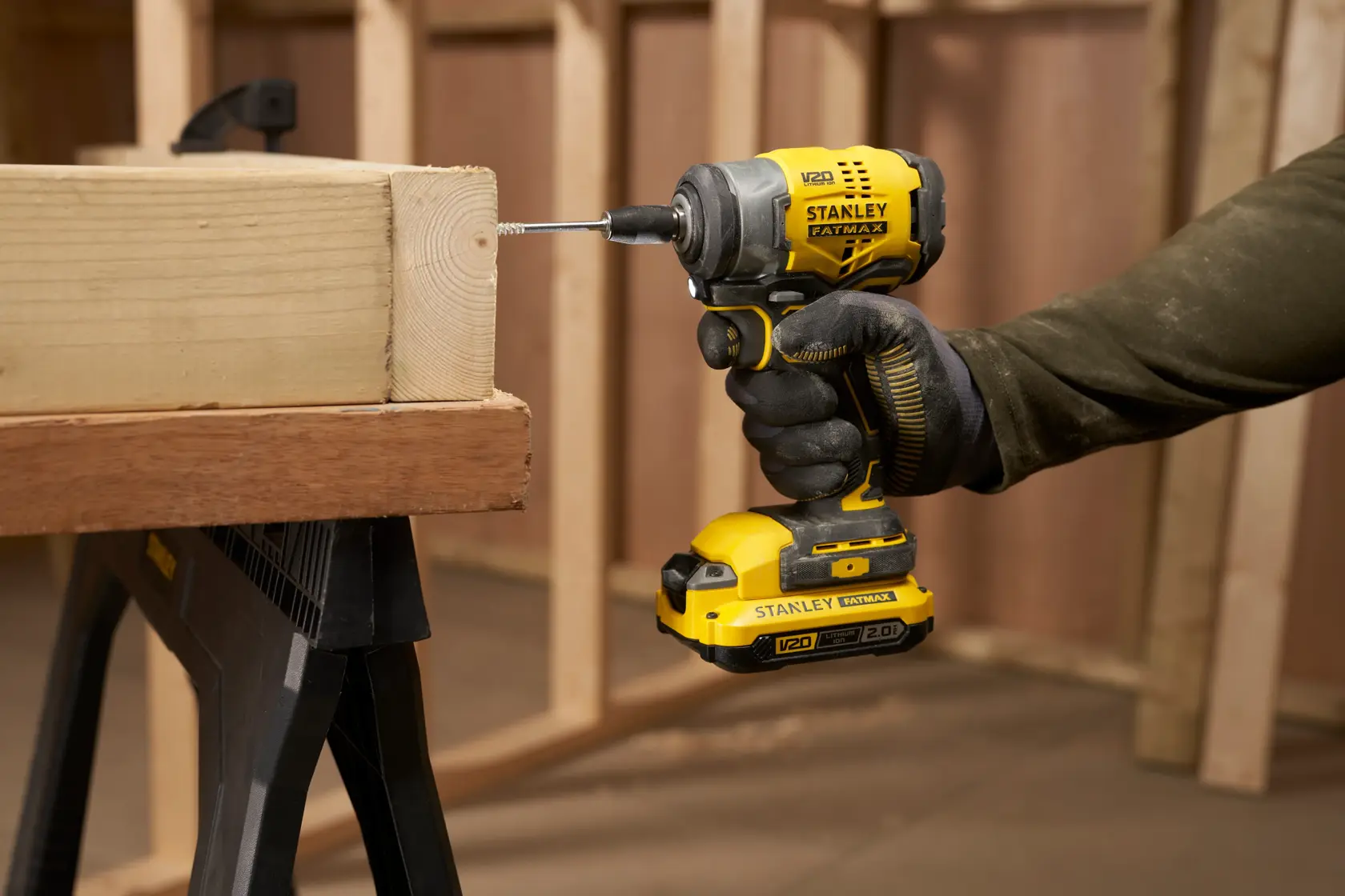 Photo of STANLEY SFMCF910B cordless impact driver being used to drive a screw into wood at a construction site.