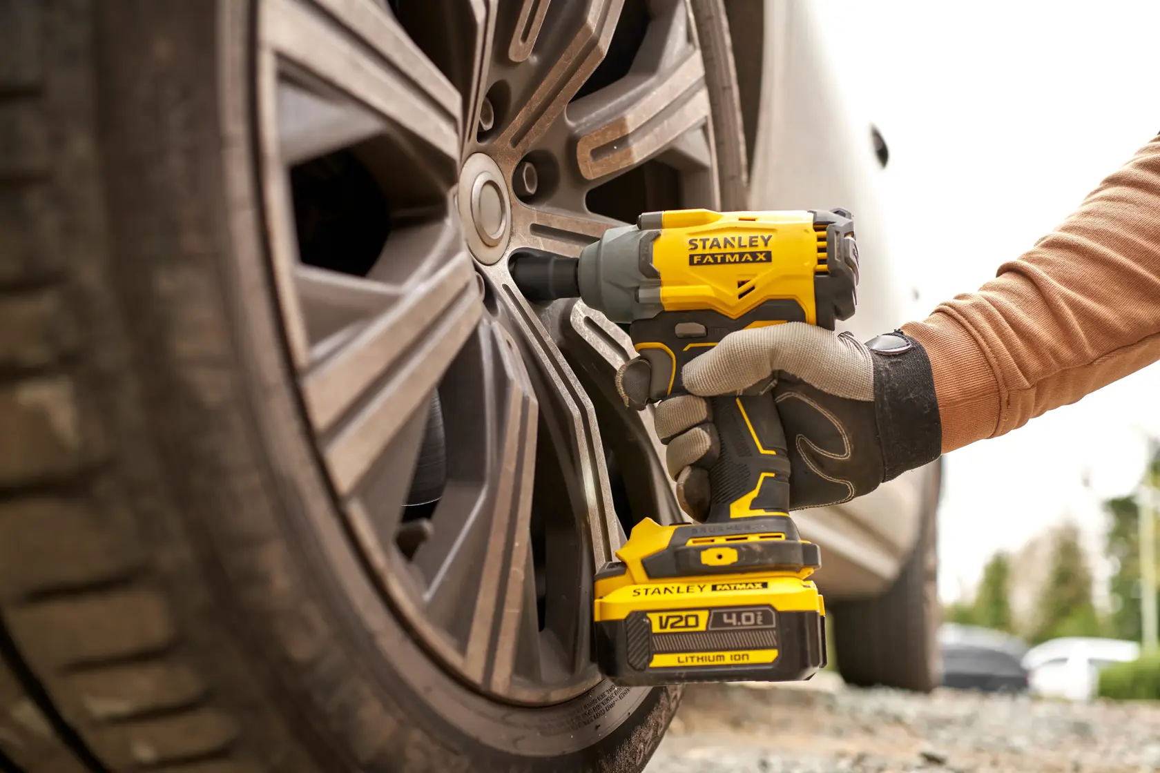 STANLEY SFMCF920B cordless impact wrench used on car wheel, close-up outdoor.