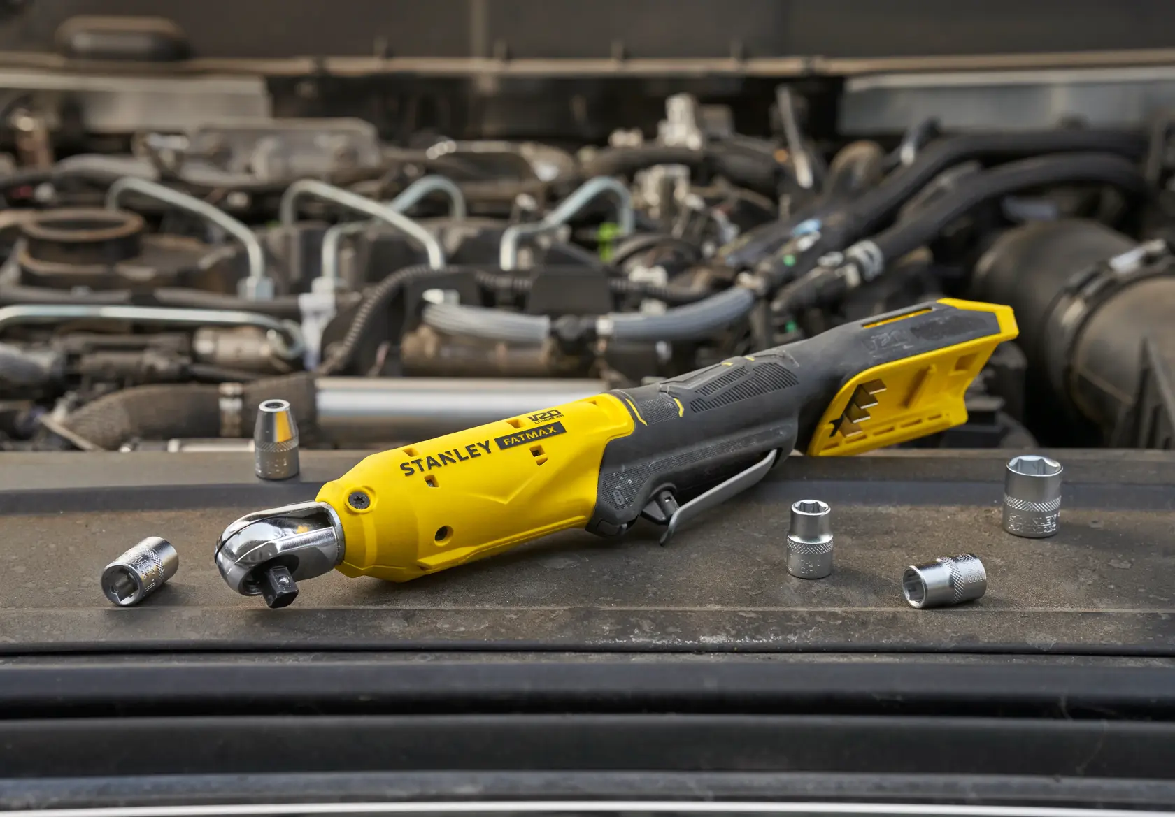 STANLEY SFMCF930B cordless ratchet tool with sockets shown on car engine photography.